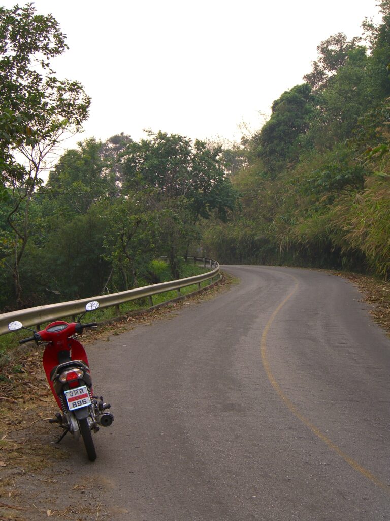 A motorcycle sits on the &quot;easy,&quot; curving road up Doi Tung