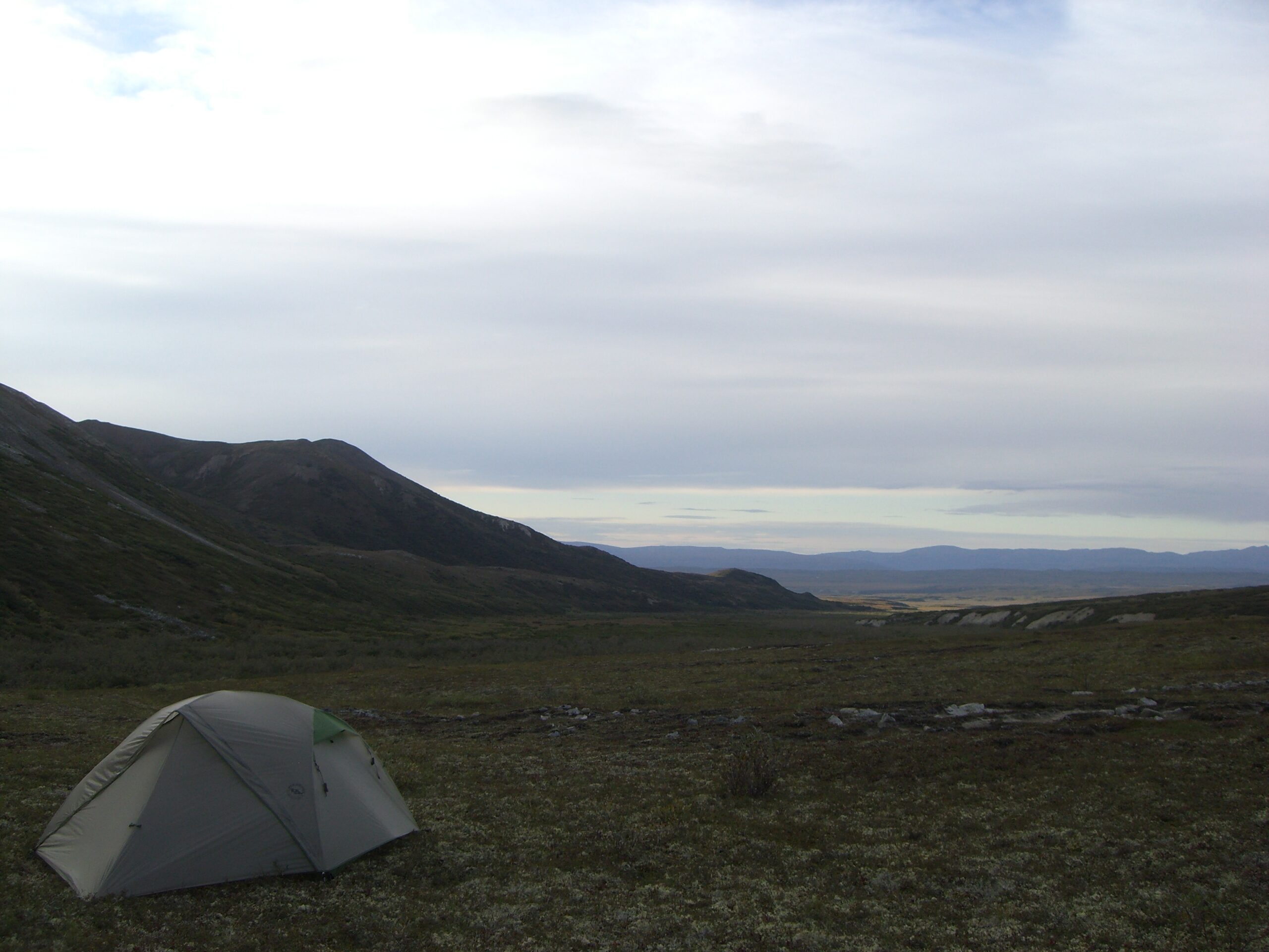 Our tent sits in a mountain pass under an overcast sky in Denali, Alaska.