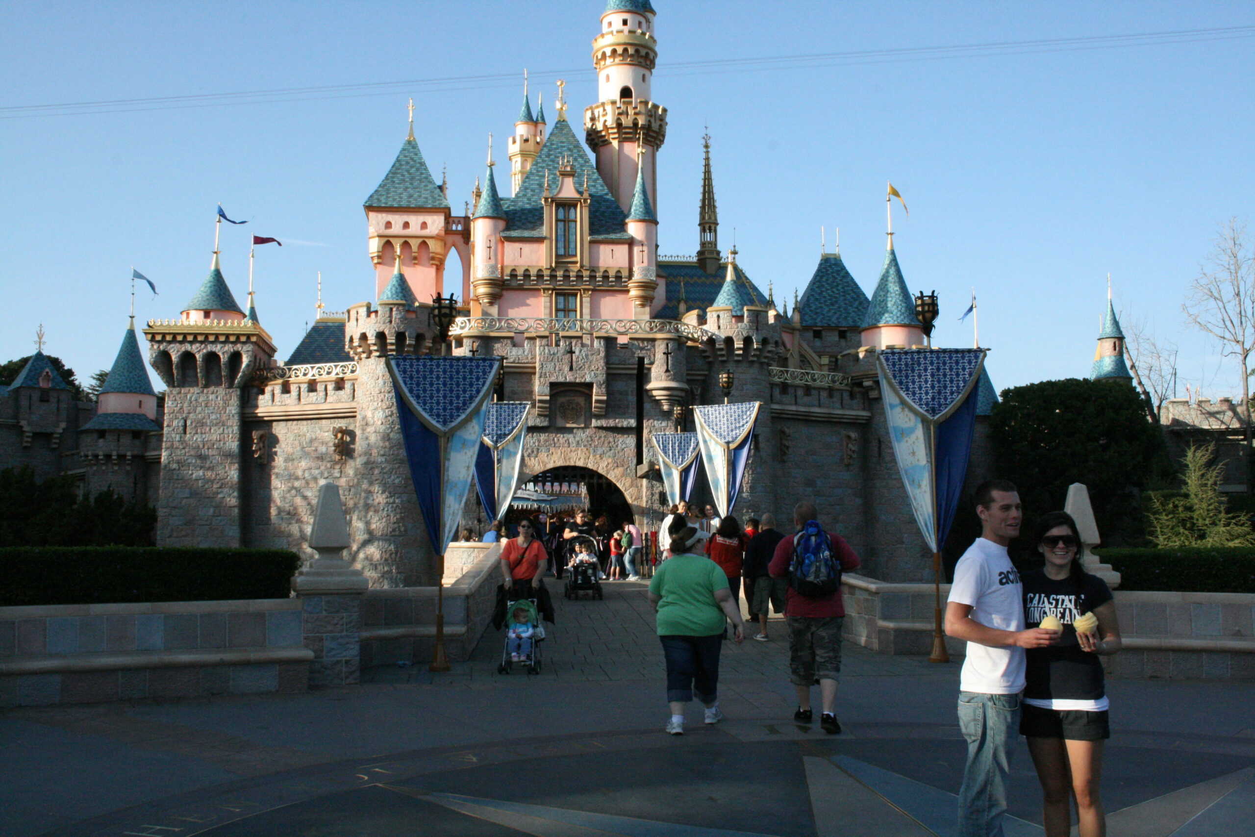 Couples enjoy posing for photos in front of Sleeping Beauty Castle in Disneyland.