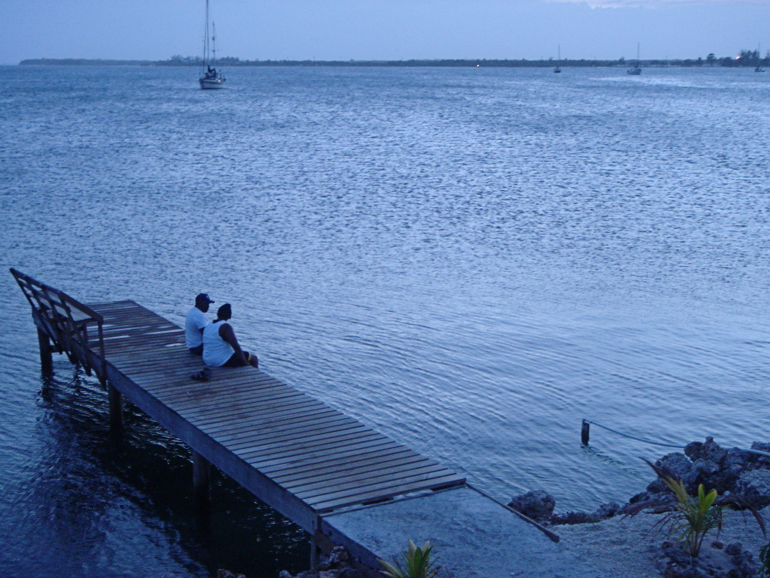 A couple looks at the horizon during magic hour in Utila, Honduras.