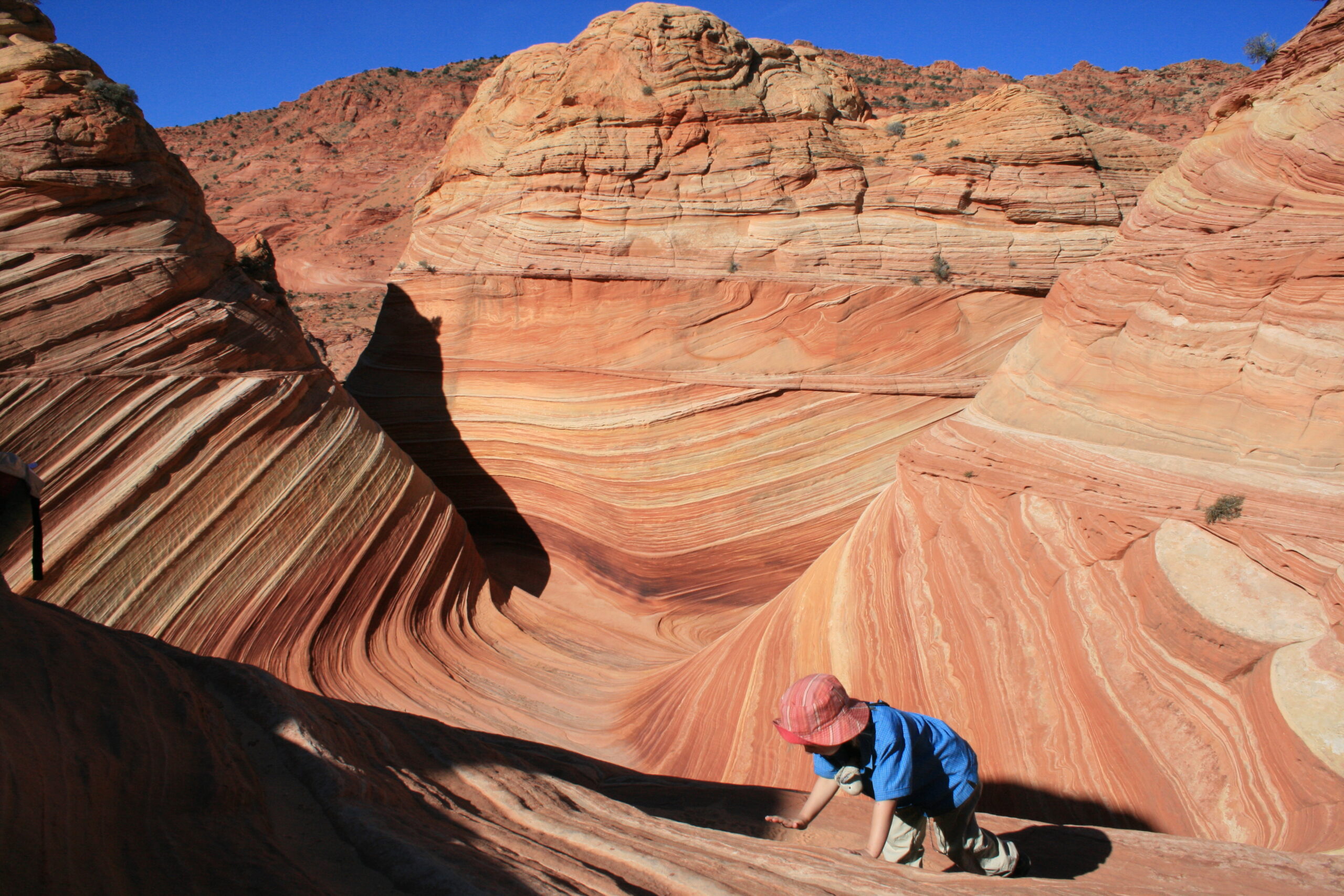 A child crawls on the red-orange sandstone at The Wave.