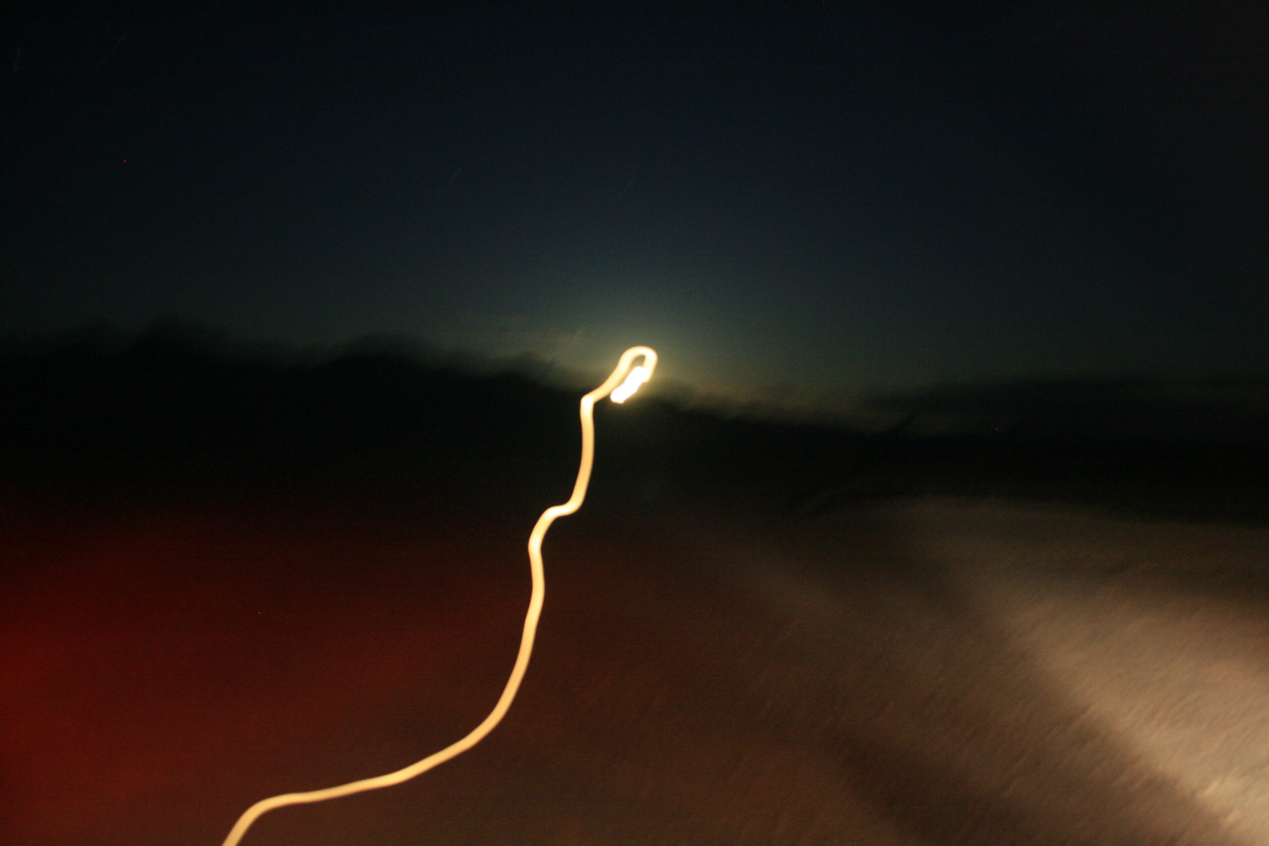 A bright white light appears behind a mountain ridge in a blurry photo taken near Area 51.