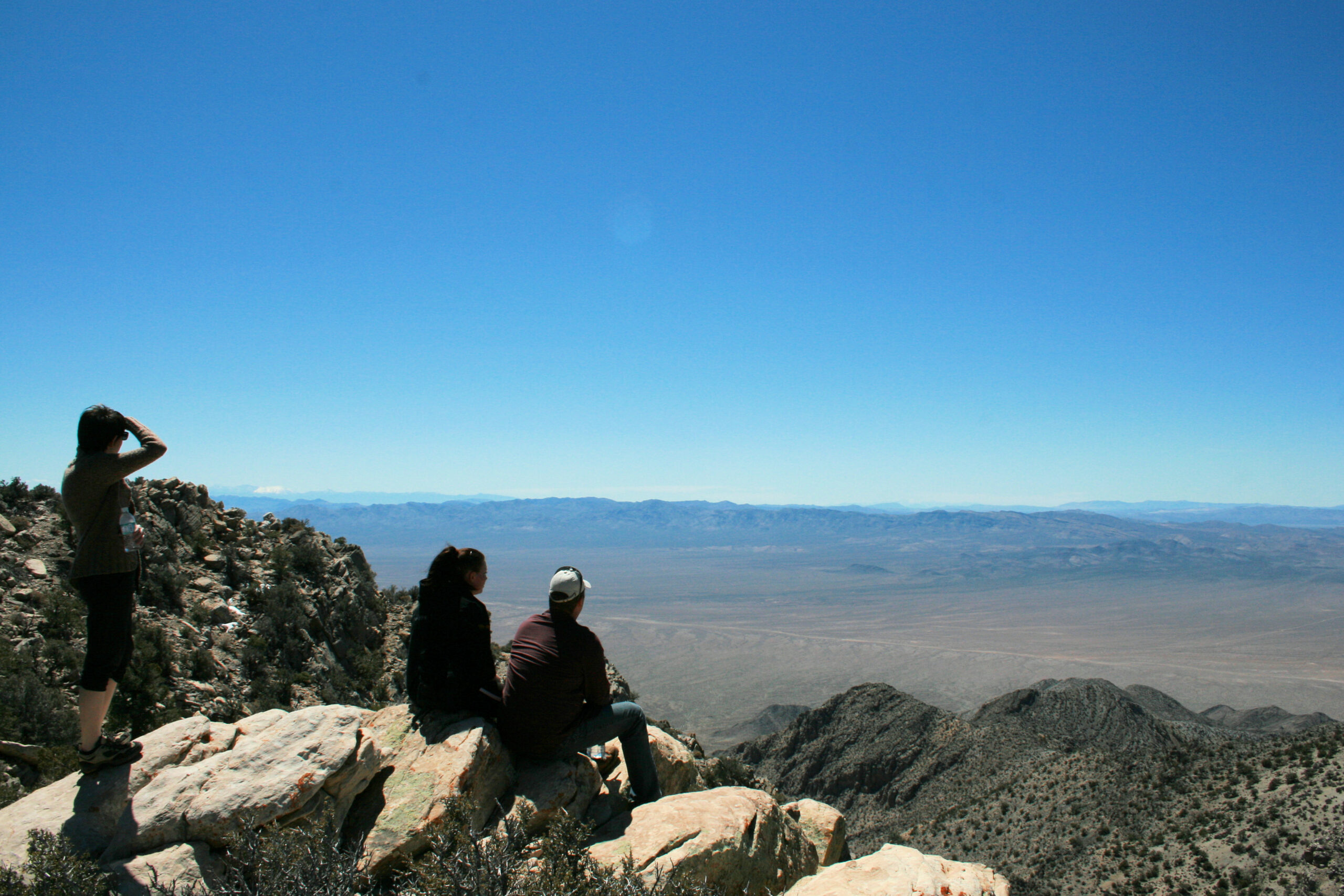 Hikers Suzanne, Wendy, and Rich look toward Area 51 from nearby Tikaboo Peak.