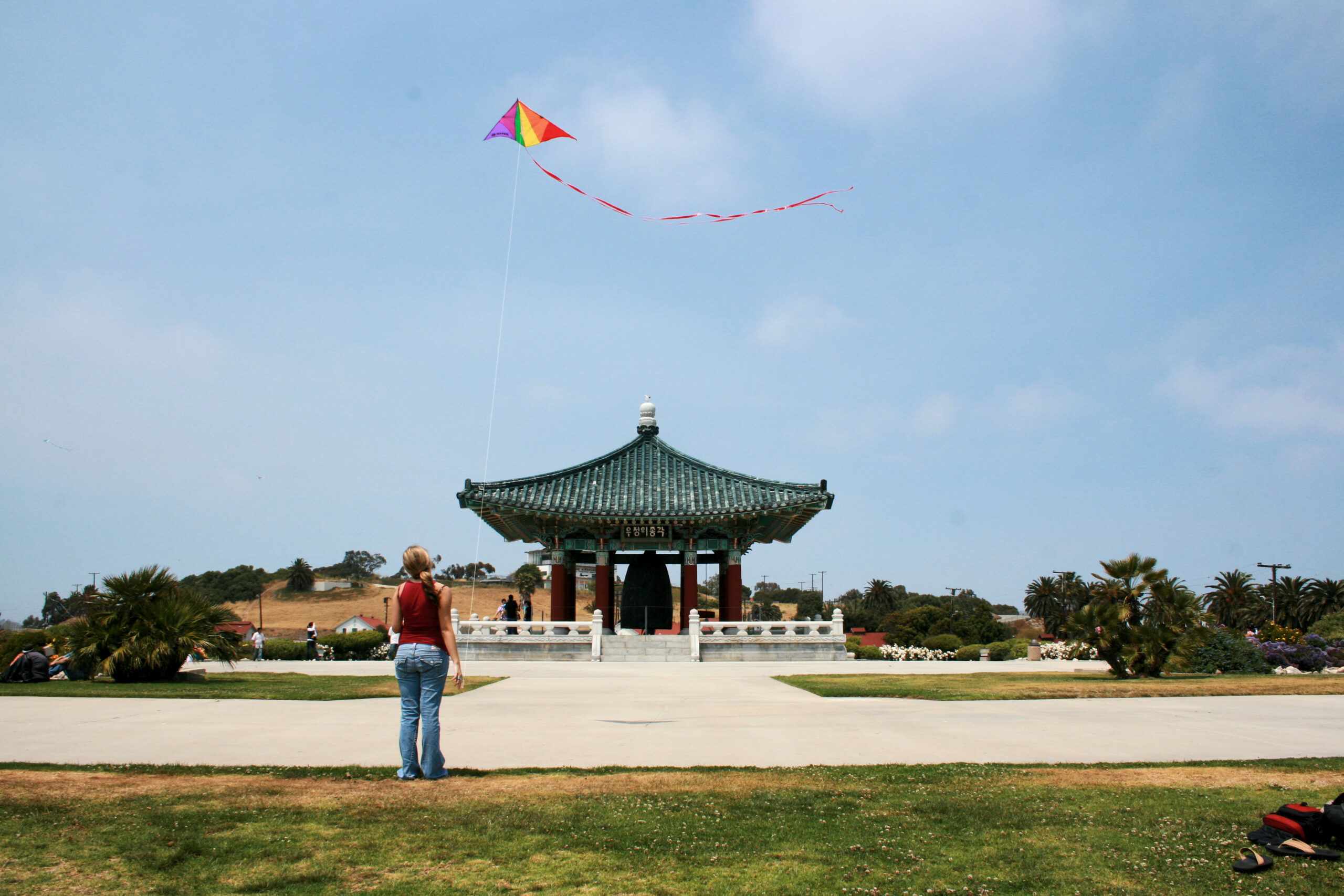 Suzy flies a kite in front of the  Korean Bell of Friendship.