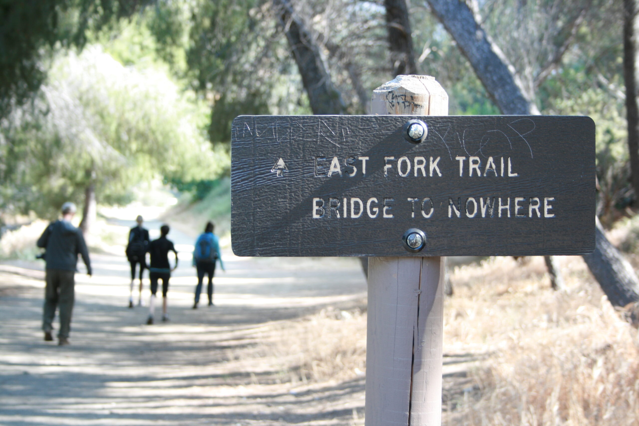 Hikers walk past the sign indicating the trail to the Bridge to Nowhere.