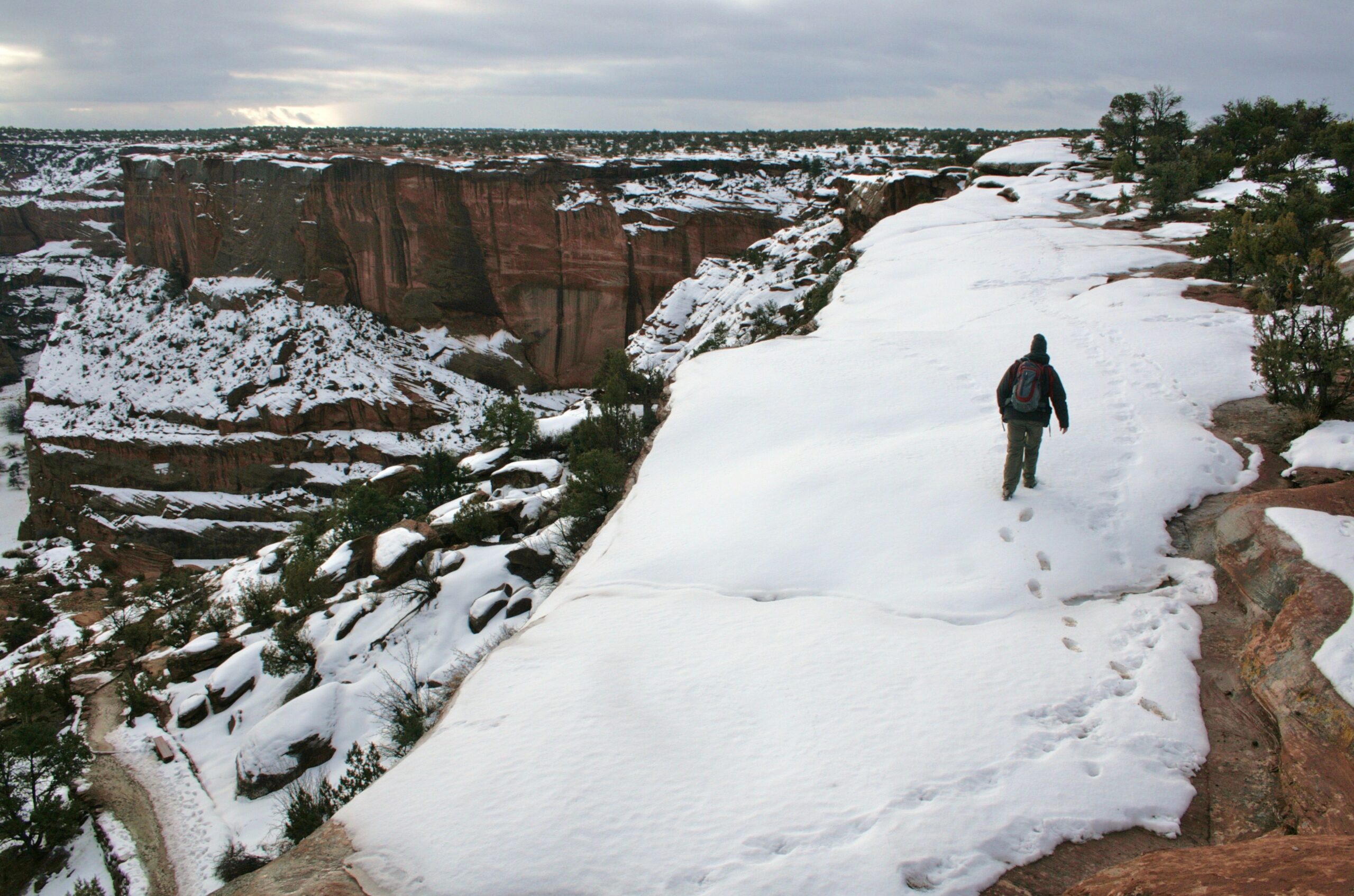 A hiker walks on a snowy ridge above Canyon de Chelly.