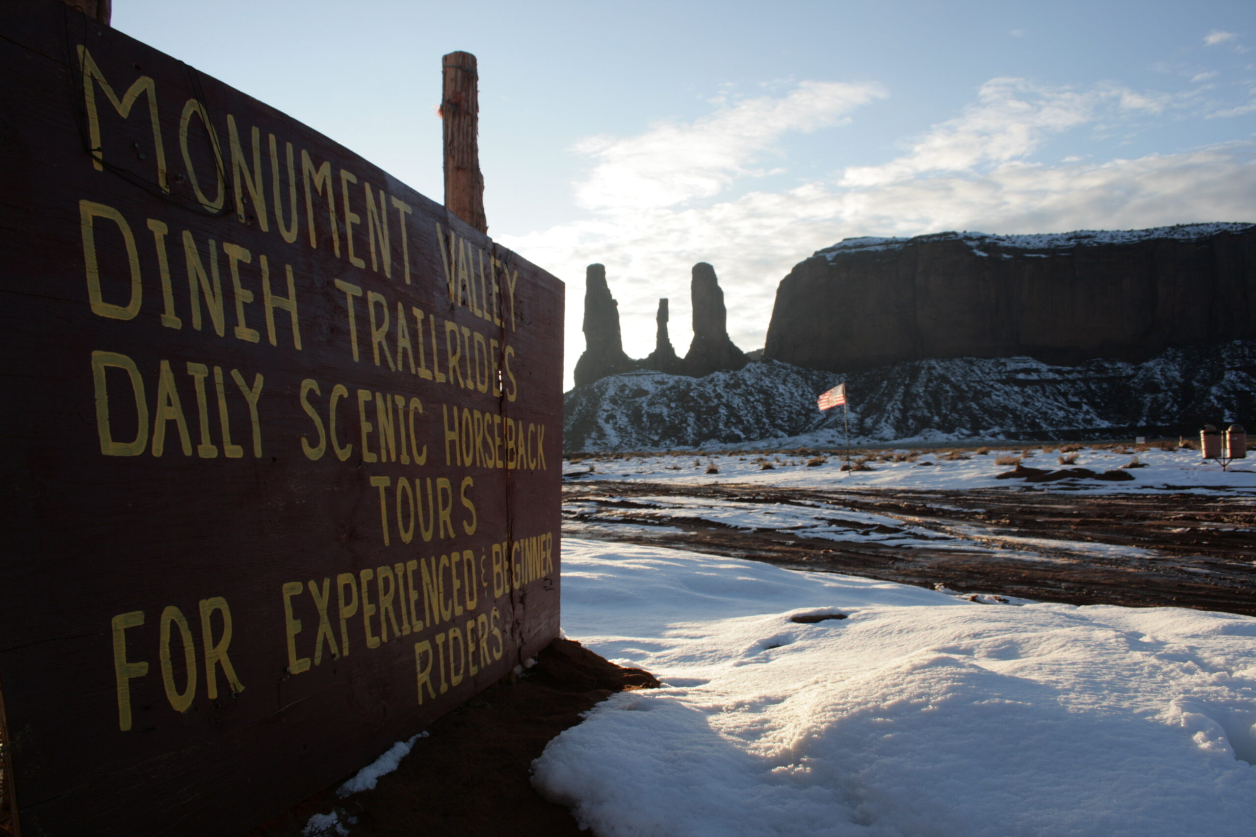 A sign advertises Monument Valley tours near the Three Fingers rock formation.