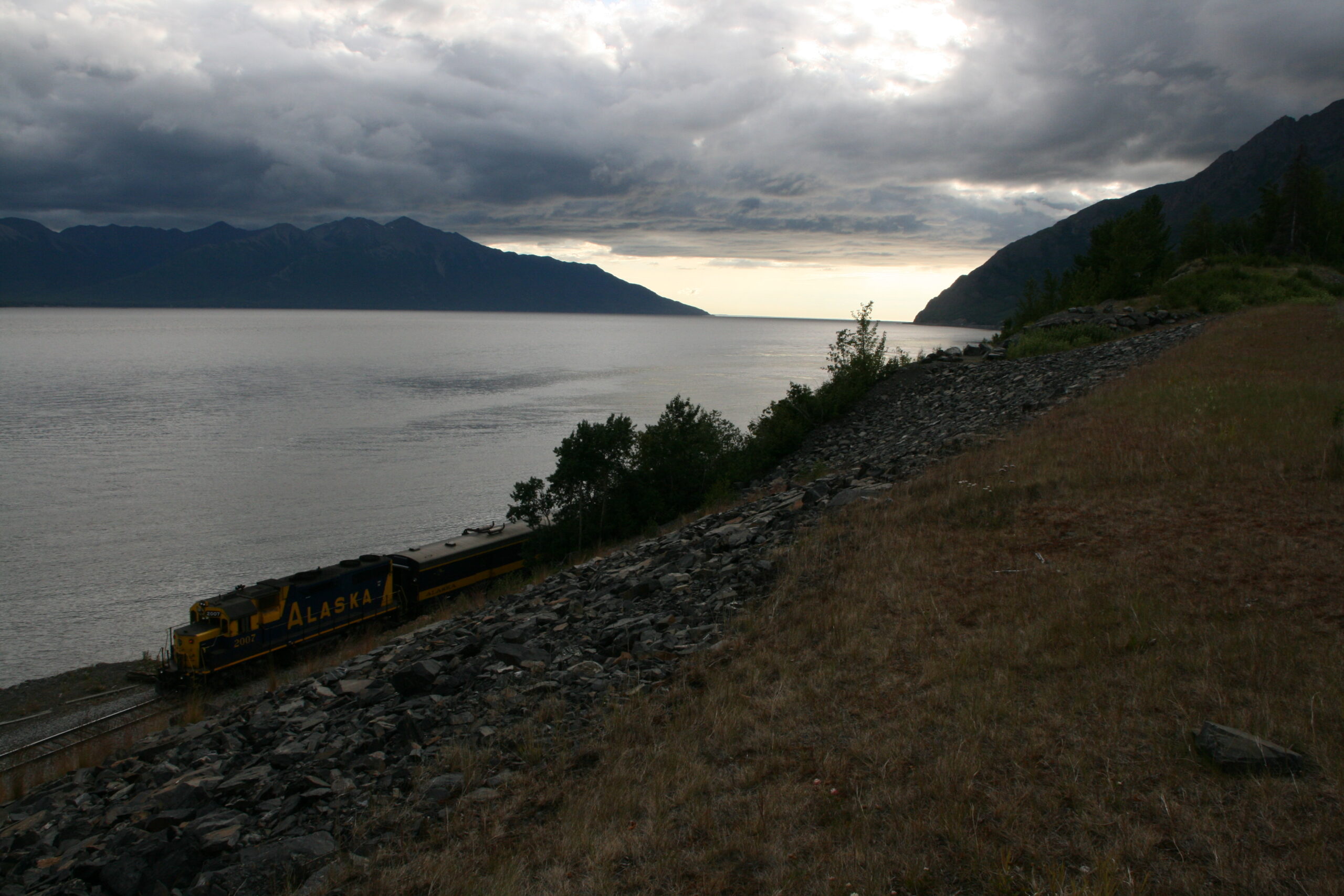 A train passes by the Cook Inlet in front of the Kenai Mountains near Alaska's Seward Highway.