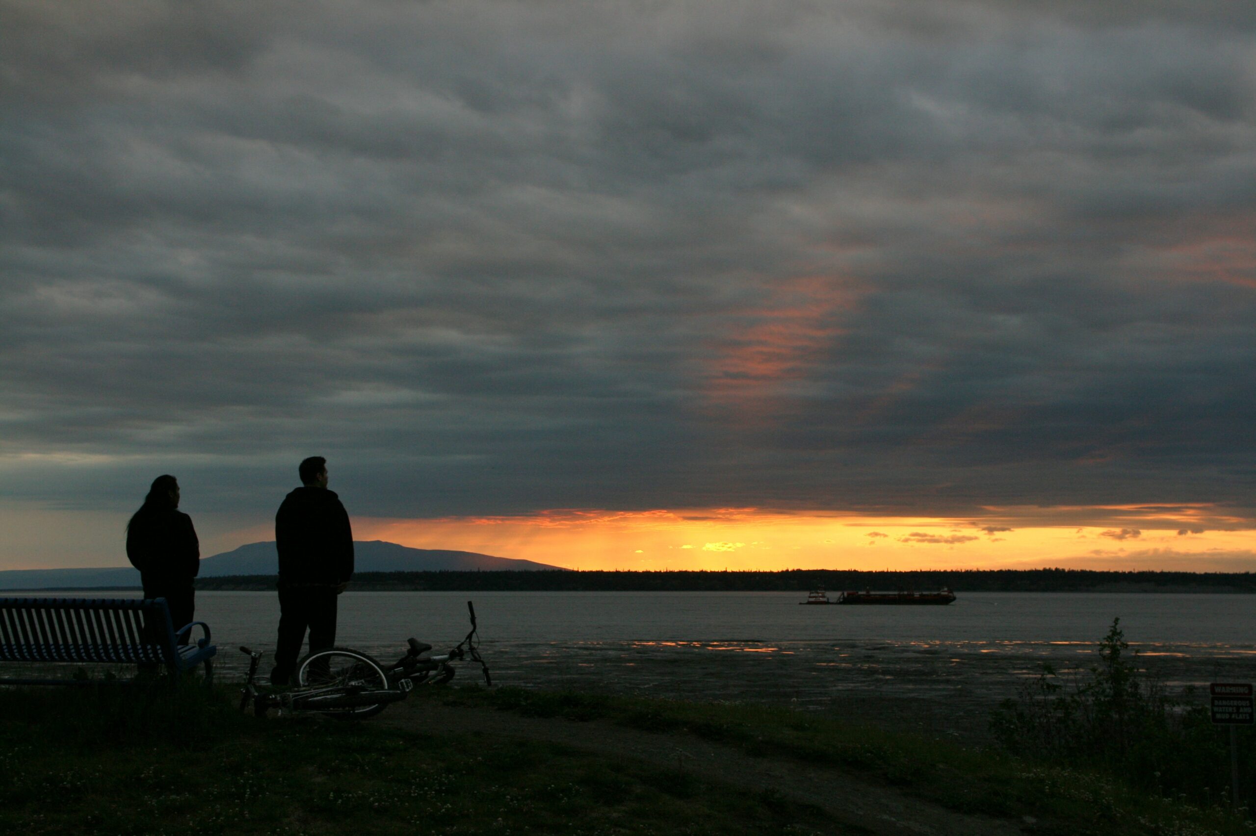 Cyclists watch the sunset from Anchorage's Coastal Trail.