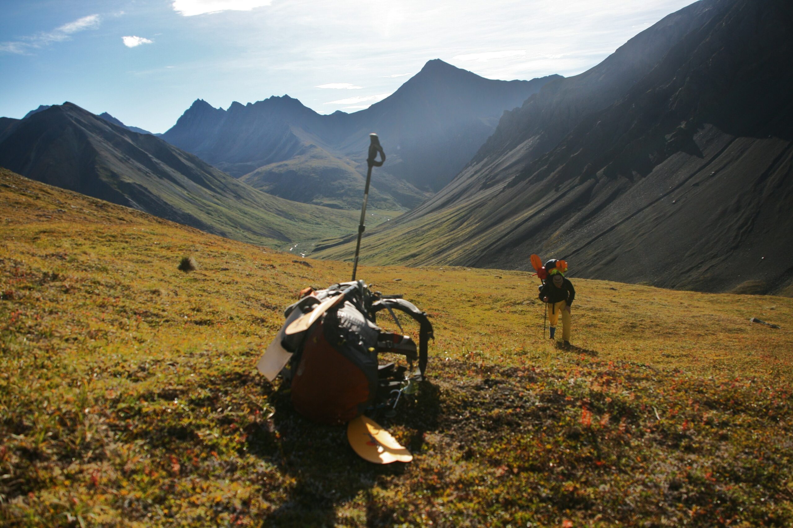 A backpack sits near the top of Windy Pass as a hiker makes his way up a steep incline.