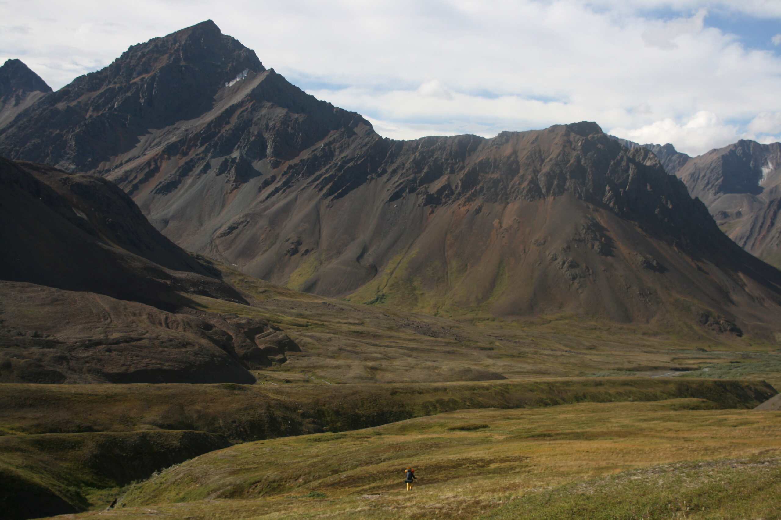 Mitch hikes below mountain peaks into Refuge Valley.