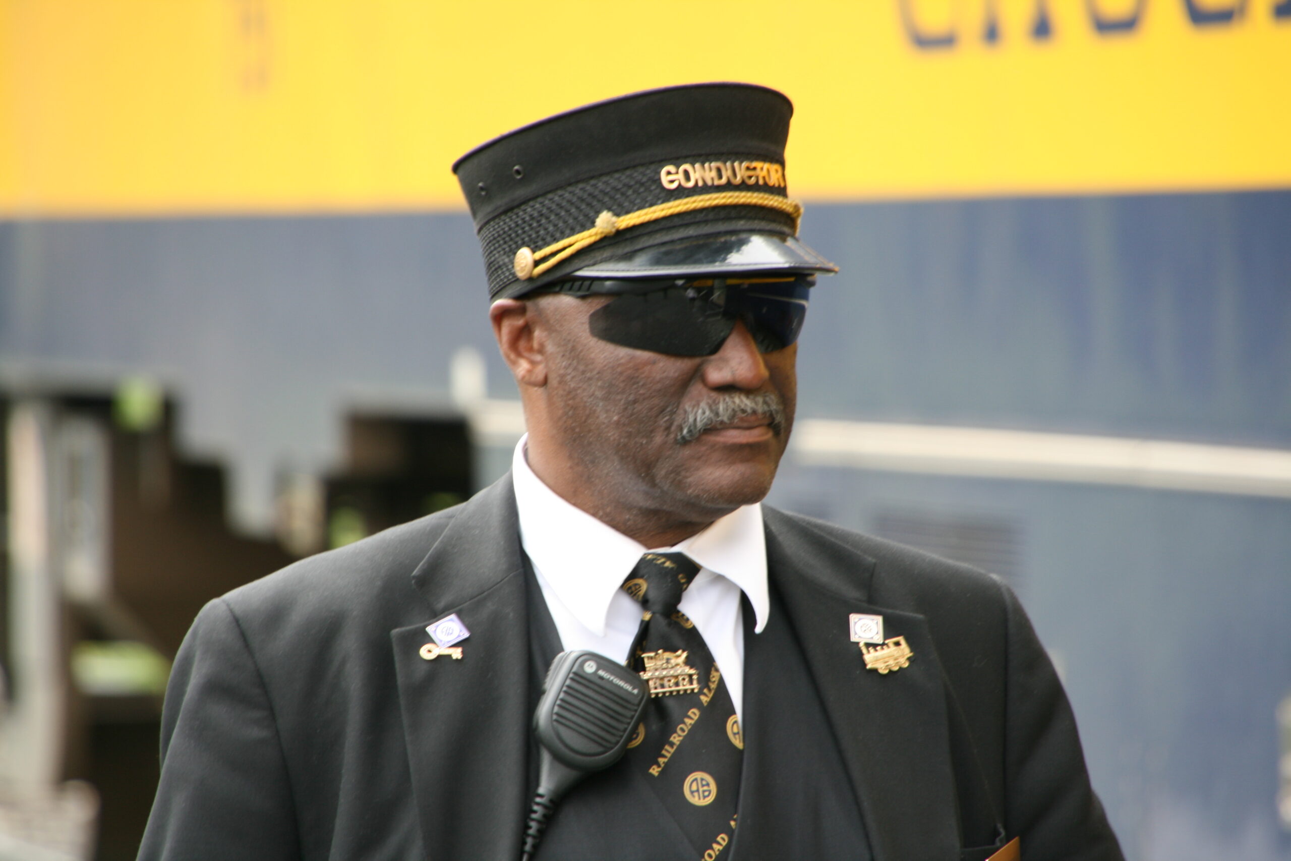 An Alaska Railroad conductor watches as tourists board his train.