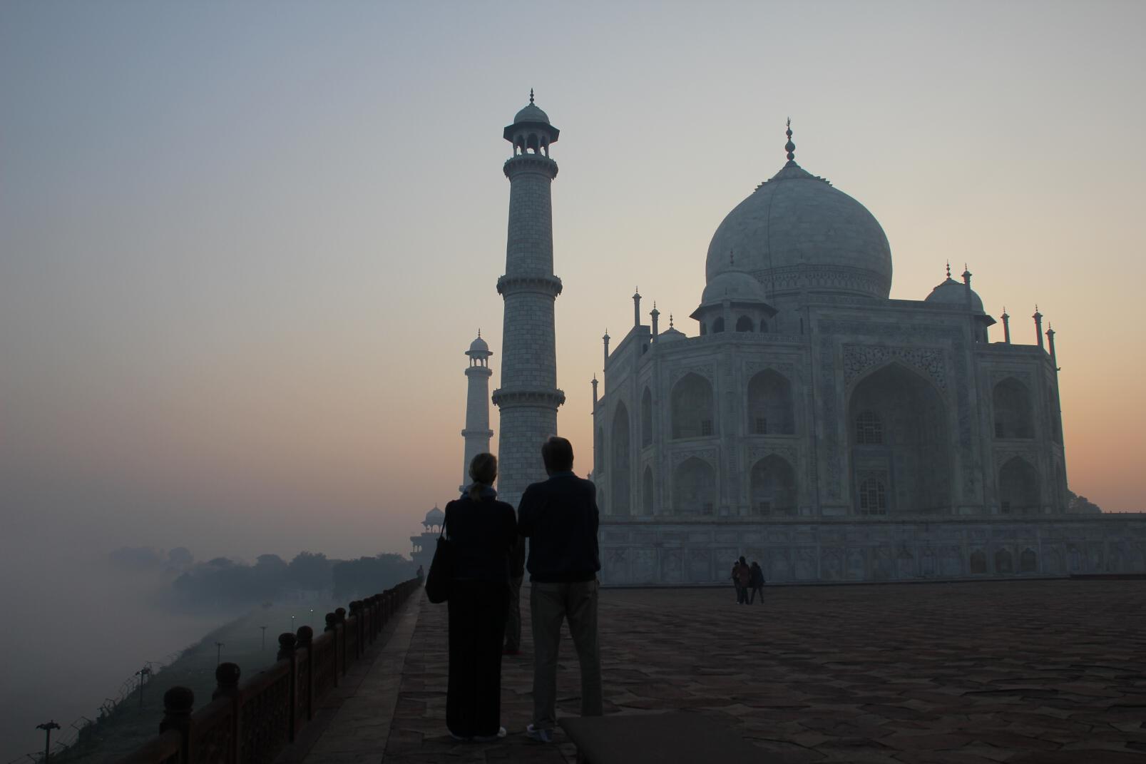 A couple gazes at the Taj Mahal from the bank of the Yamuna River.