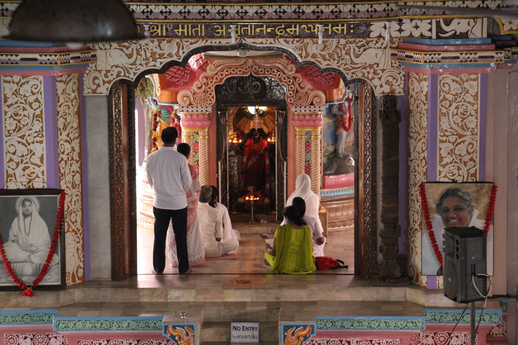 Amma followers worship in front of a statue of Kali in the temple at Amritapuri next to a large photograph of Amma.