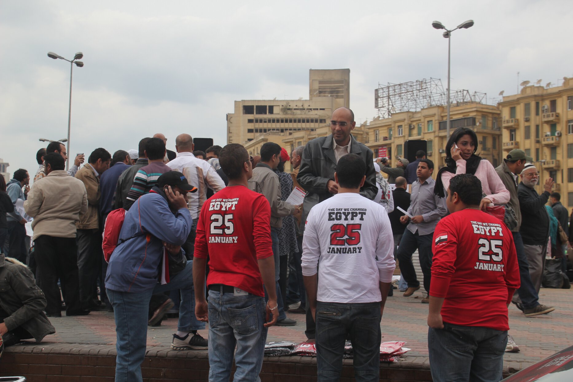 Demonstrators sell &quot;The Day We Changed&quot; T-shirts while protesters gather in Cairo&#039;s Tahrir Square.