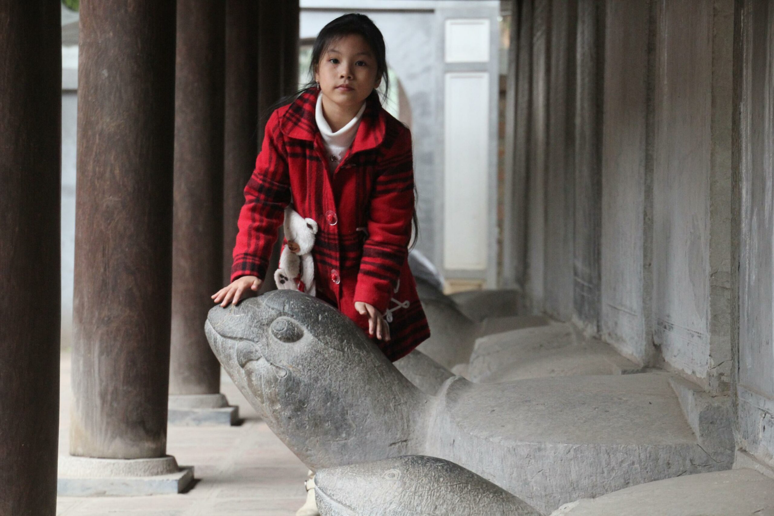 A young girl rubs the head of a statue of the Hoan Kiem turtle in Hanoi's Temple of Literature.
