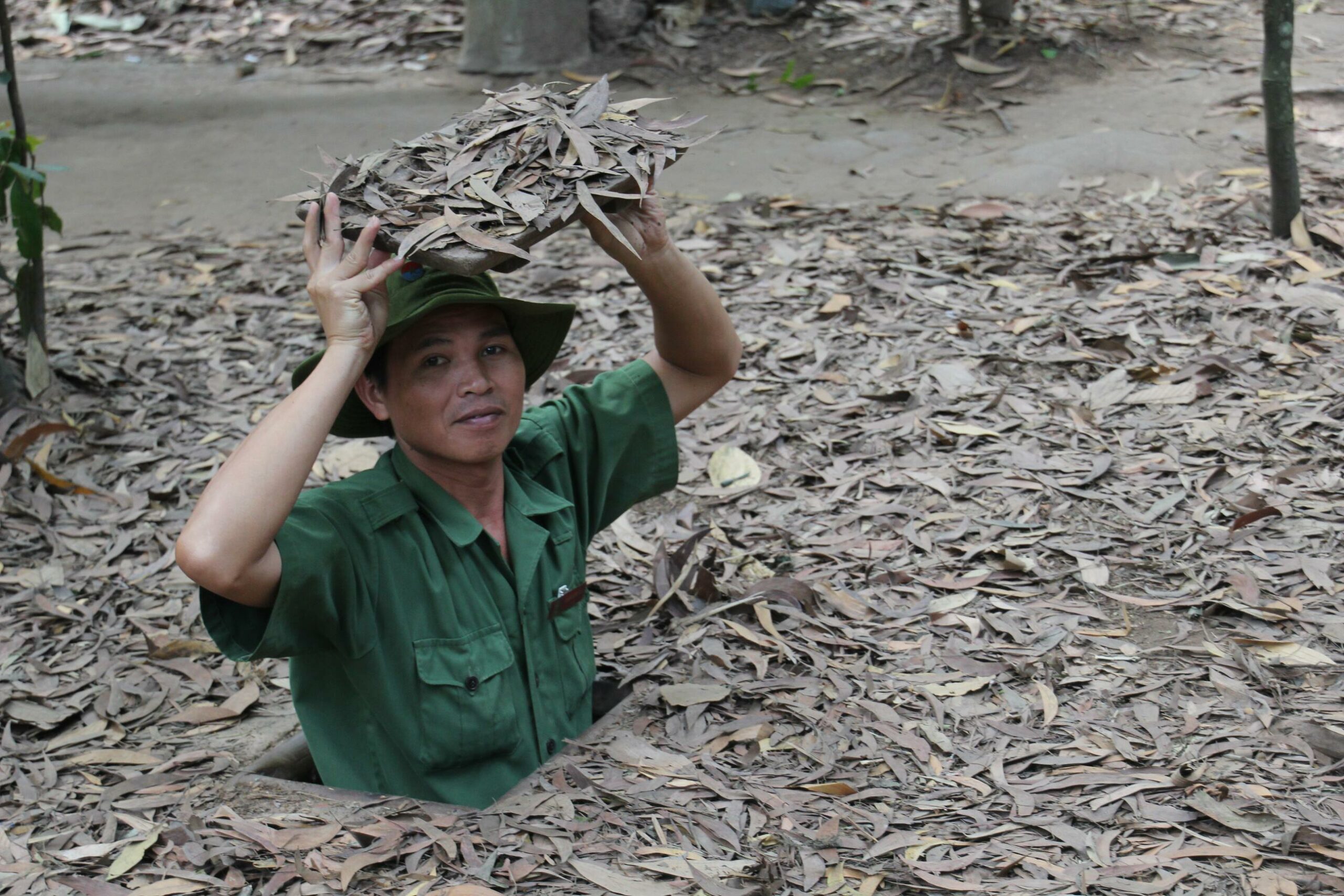 A man demonstrates how Cu Chi Tunnel entrances were camouflaged during the Vietnam War.