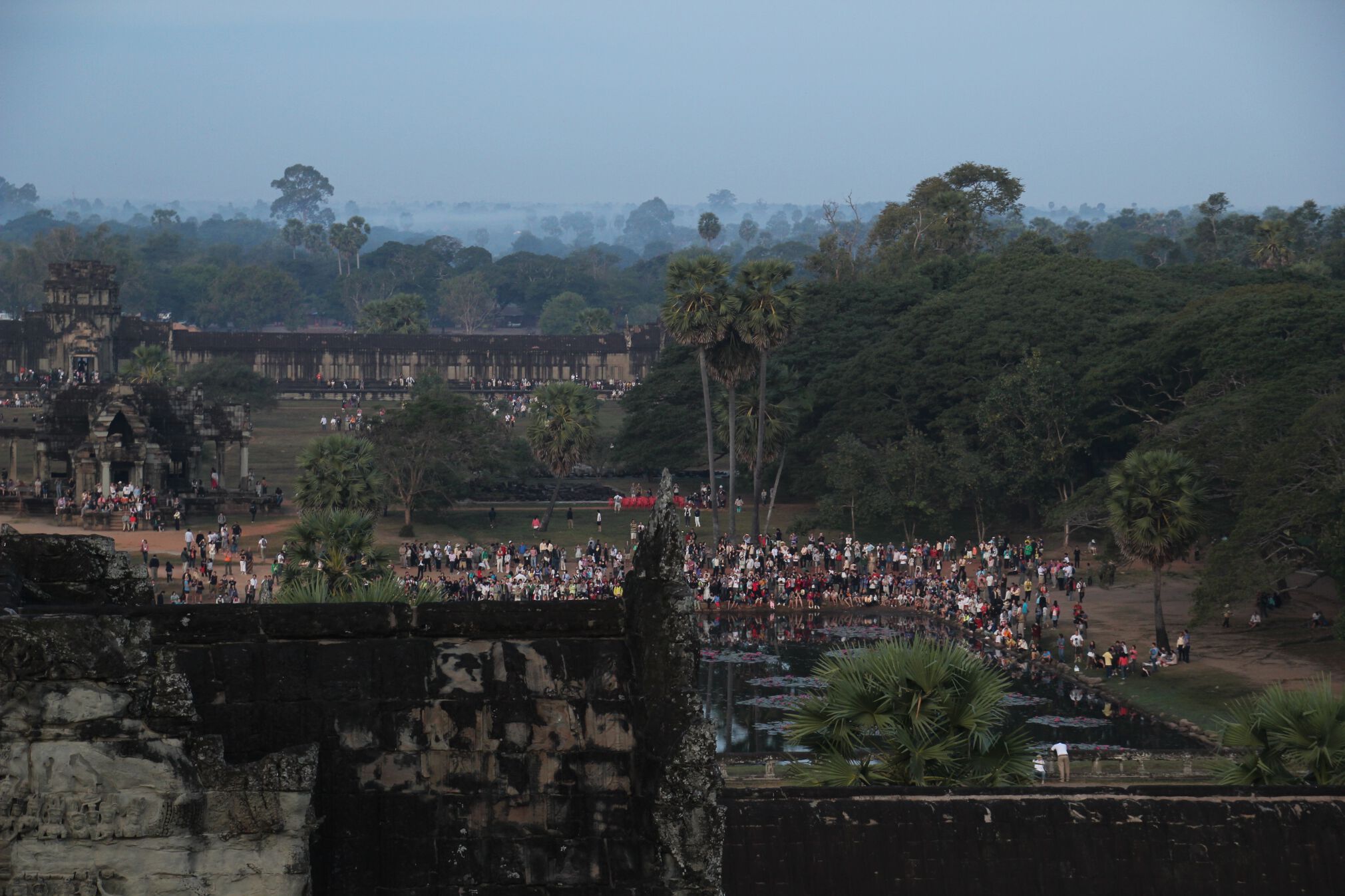 Tourists, as seen from the top of Angkor Wat, gather around the temple's reflection pool.