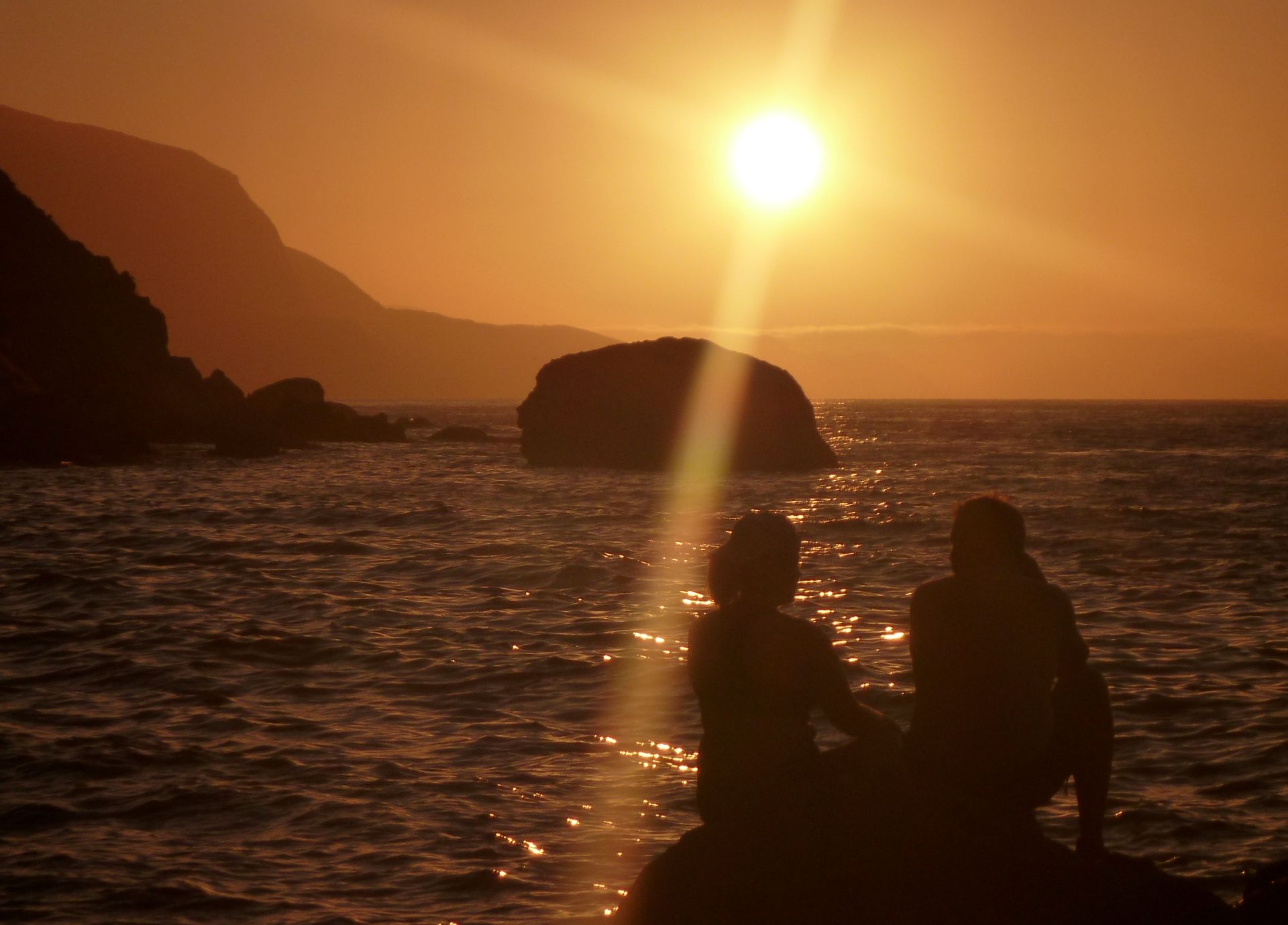 Kayakers relax on a rock at sunset on Catalina Island.