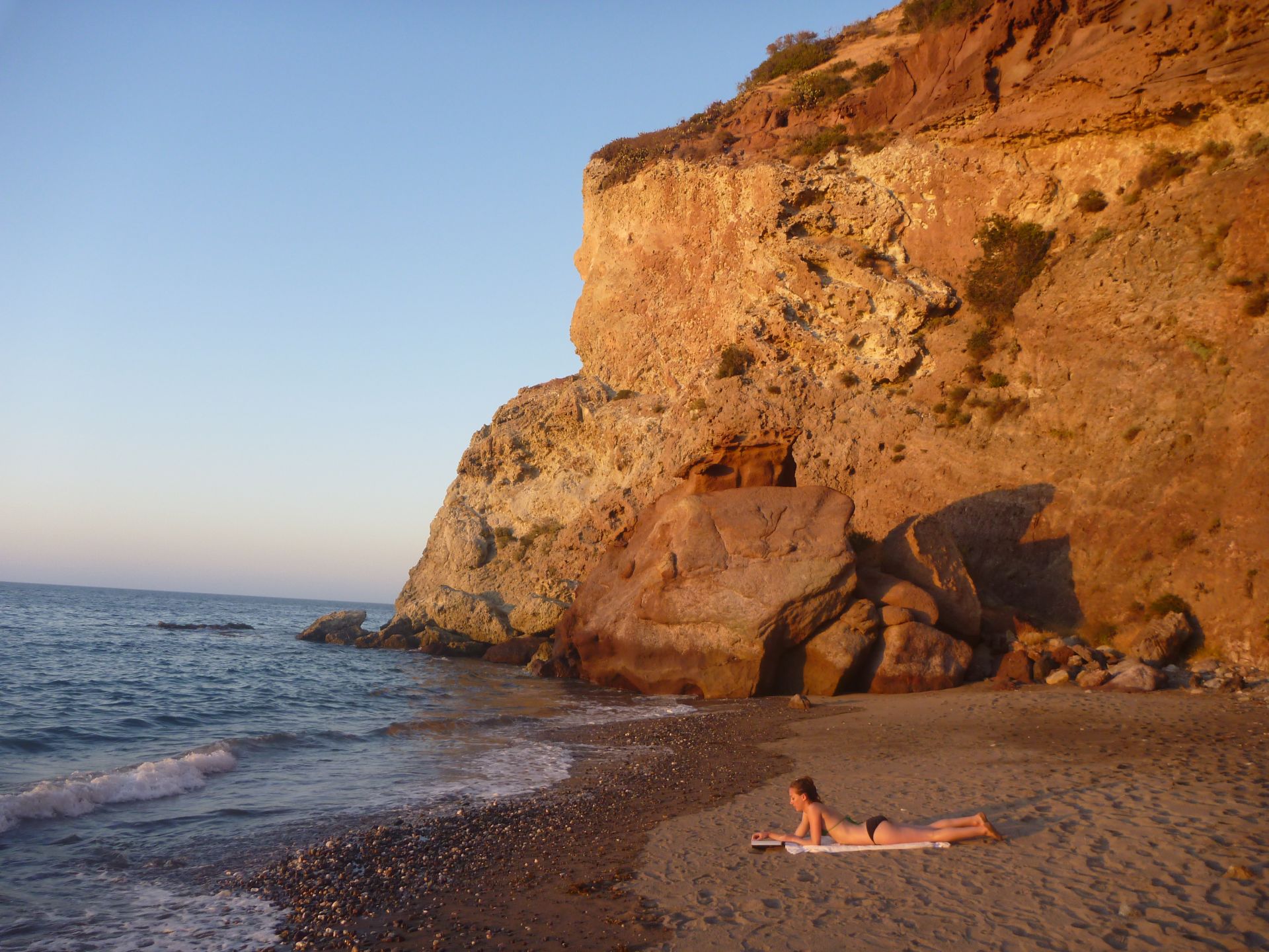 A woman reads a book on secluded Lava Wall beach on Catalina Island, California.