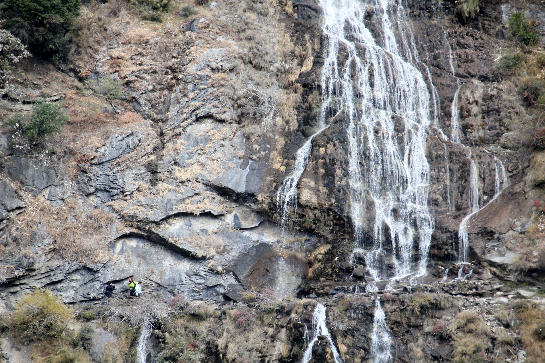 Hikers walk near a waterfall in in China's Tiger Leaping Gorge.