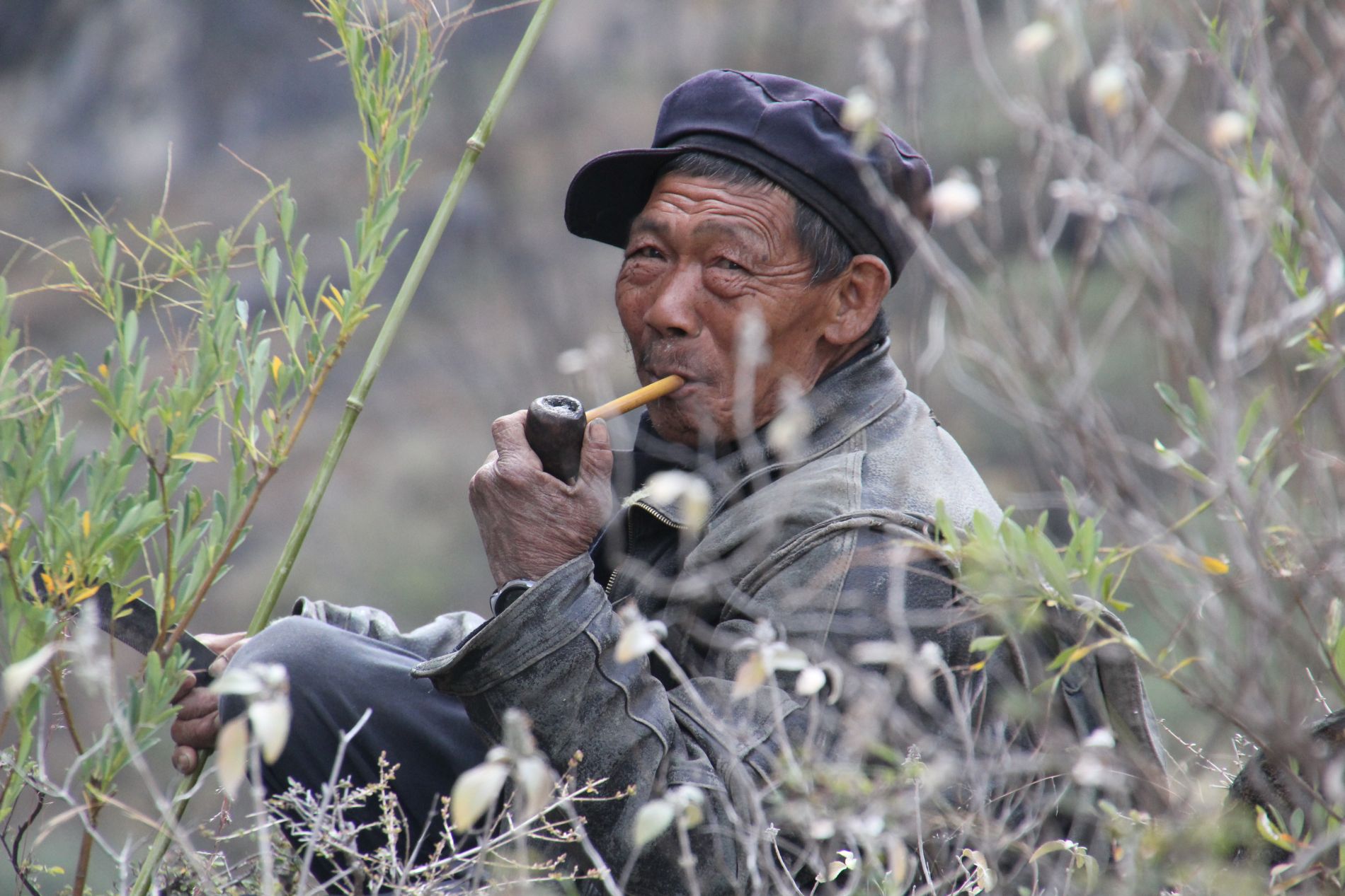 A Chinese farmer takes a break, smoking a pipe in China's Tiger Leaping Gorge.