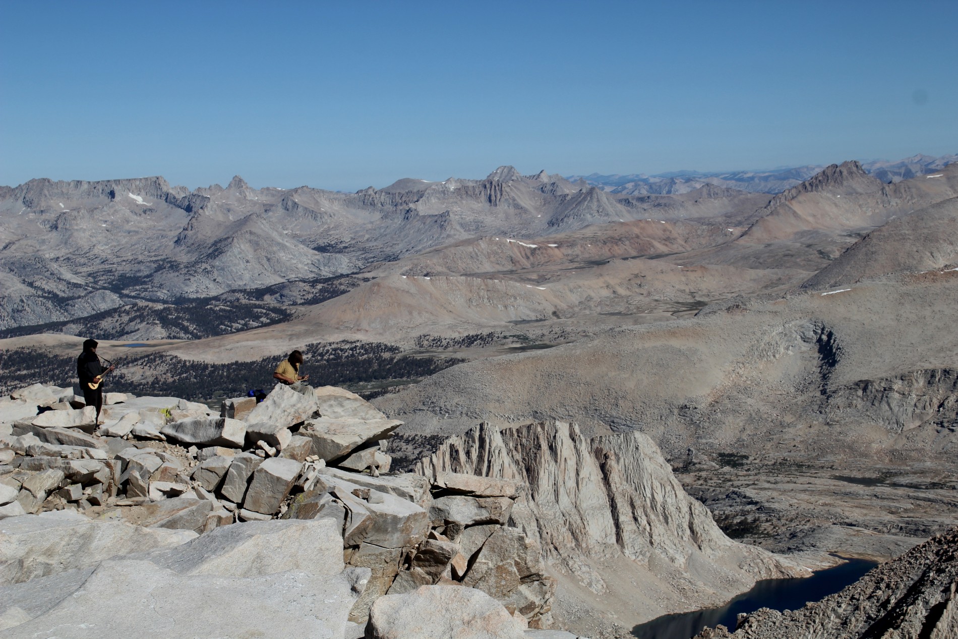 Men play a drum pad and a ukelele on the Mount Whitney summit.