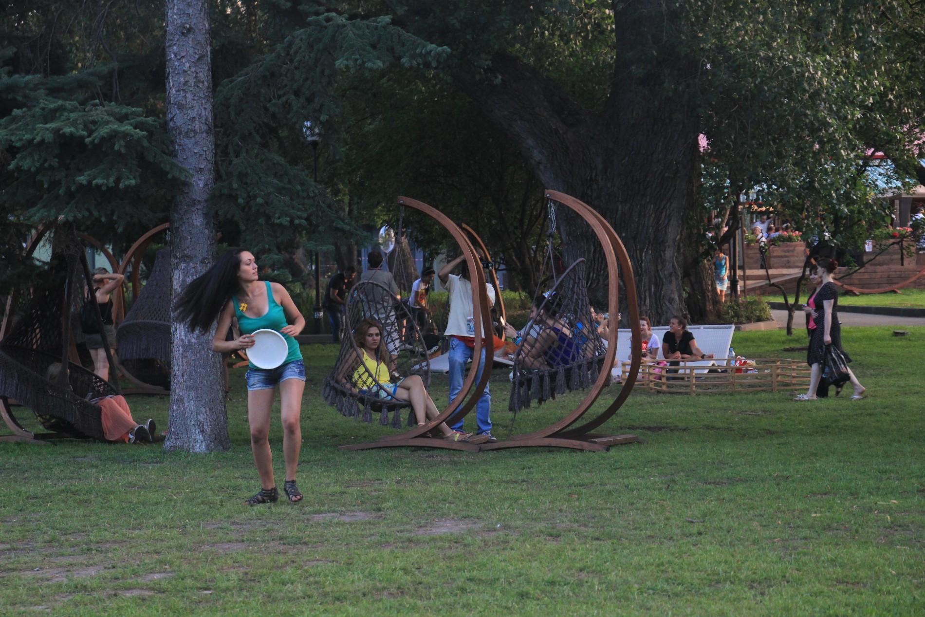 A woman prepares to throw a Frisbee while people watch from chair swings in Moscow's recently renovated Gorky Park.