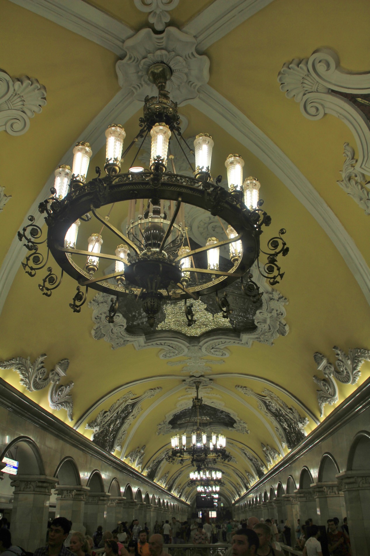 The Moscow Metro's Komsomolskaya Station features baroque design, Corinthian columns, arched yellow ceilings, and ornate chandeliers.