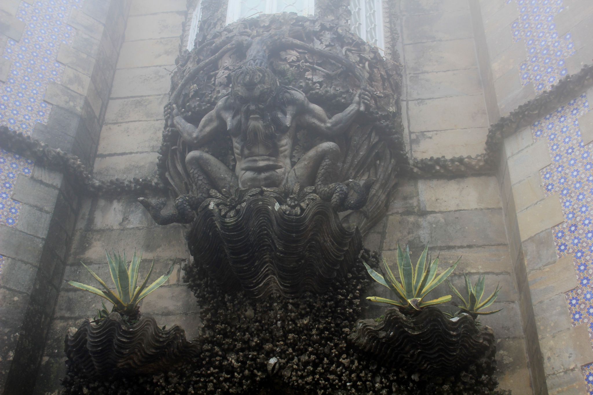 A triton emerges from a clamshell above a gate in the Pena National Palace in Sintra, Portugal.