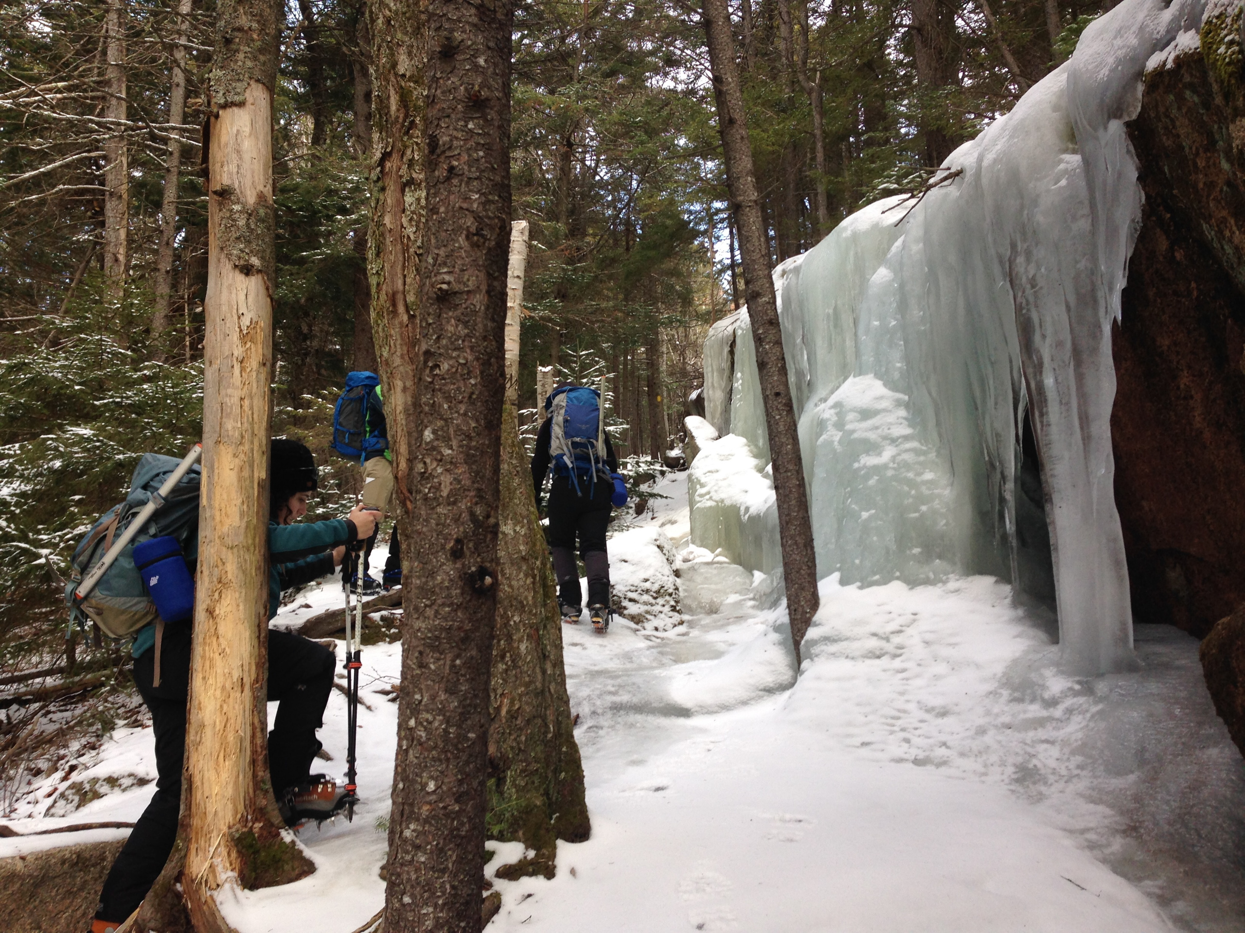 Hikers walk on ice sheets with crampons on Mount Washington.