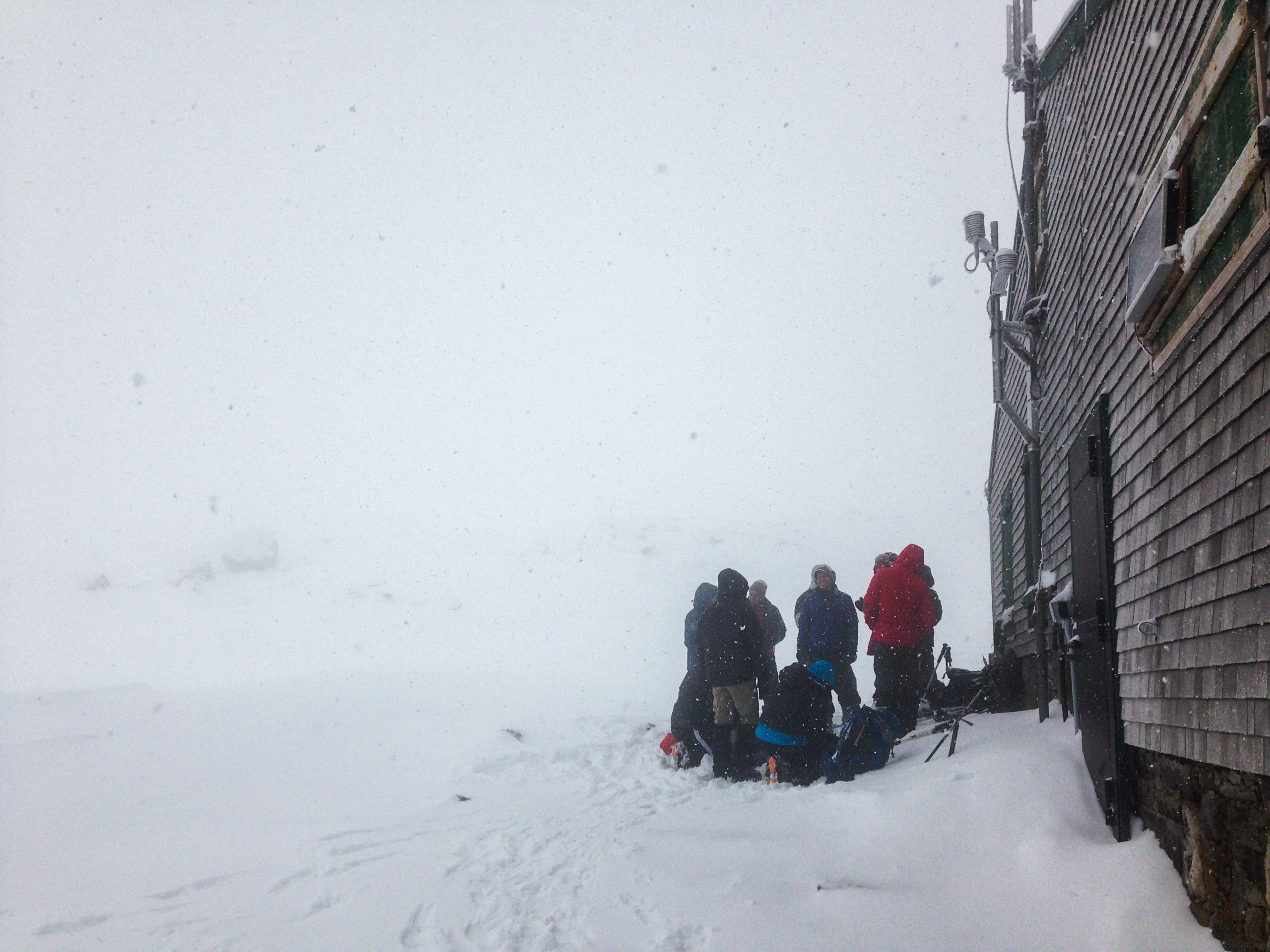 Hikers huddle next to the Lake of the Clouds Hut below Mount Washington's summit cone.