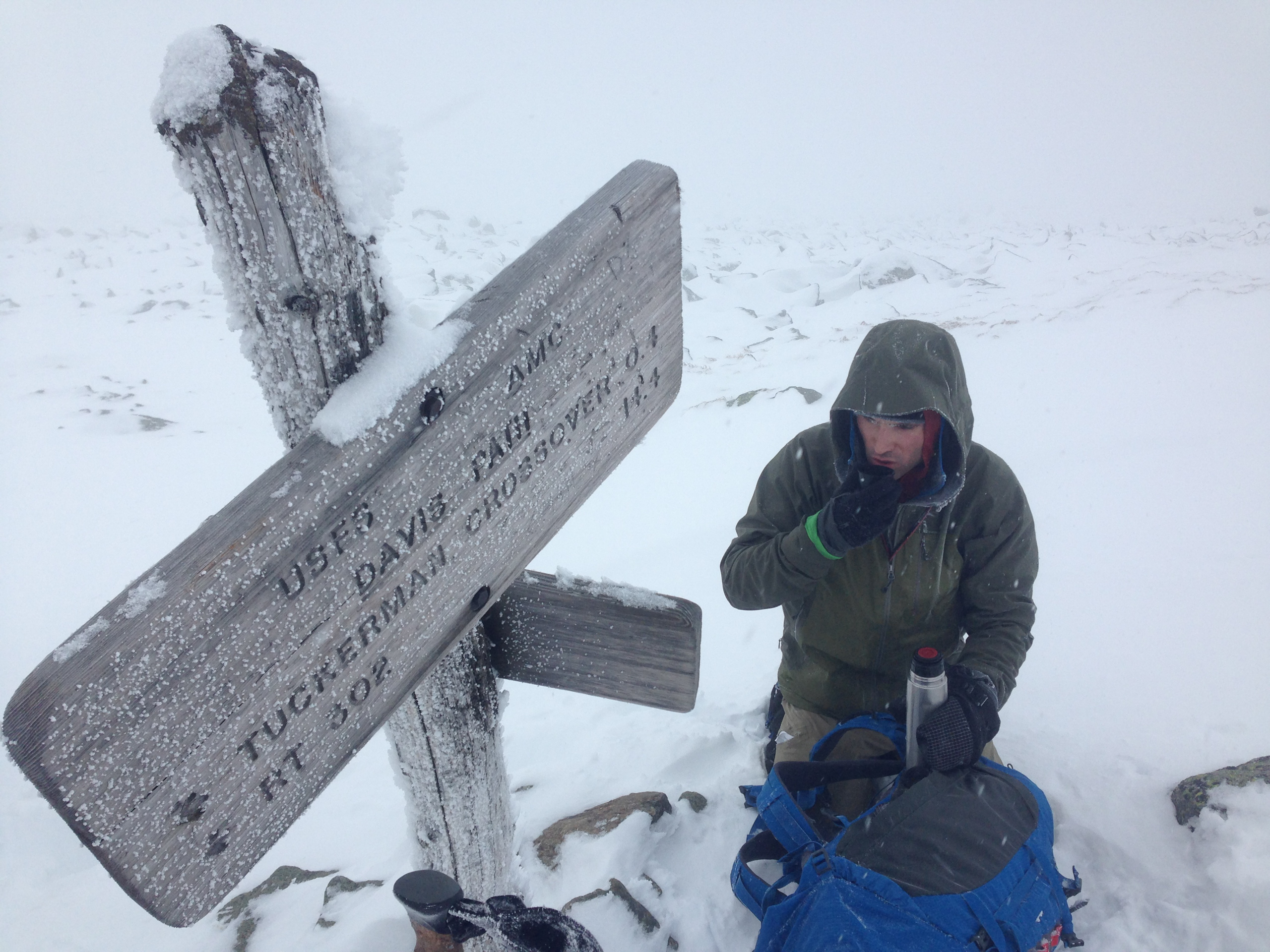 A climbing guide surveys the situation at the Tuckerman Crossover sign on Mount Washington.