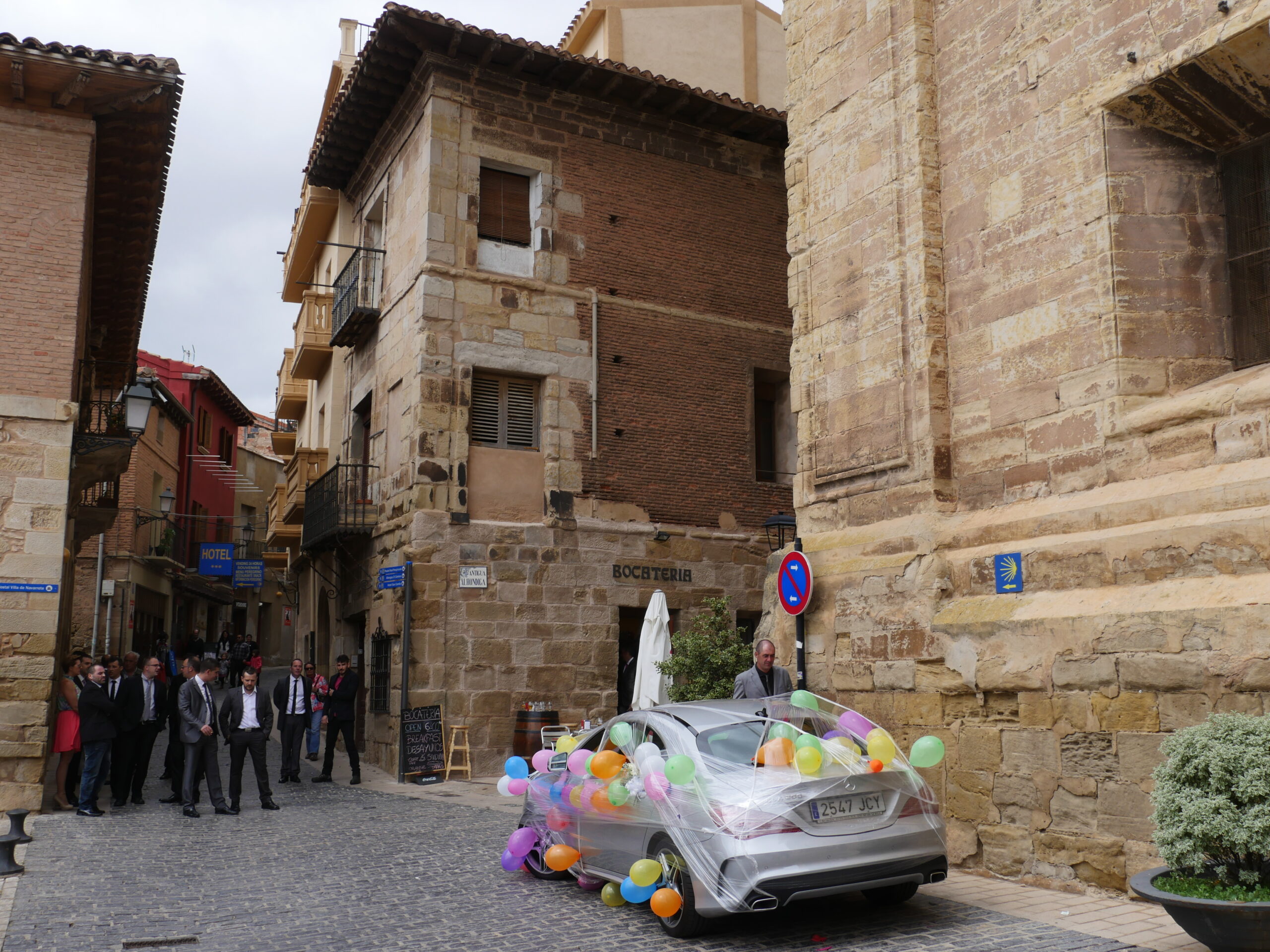 Groomsman and a decorated car sit outside the Iglesia de La Asunción in Navarrete, Spain in preparation for a wedding.