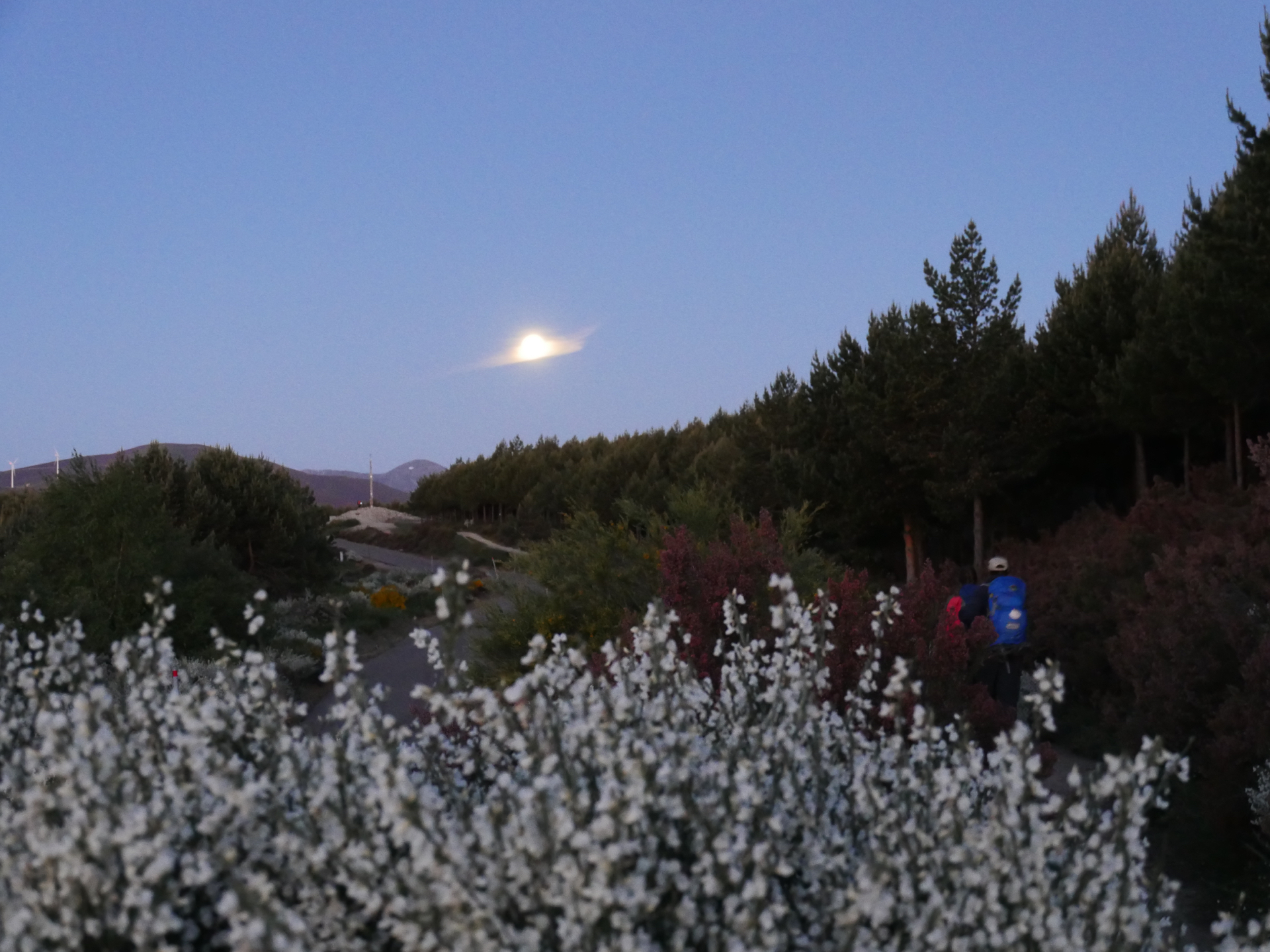 A single cloud sits in front of a full moon above Cruz Ferro, near the high point of the Camino de Santiago.