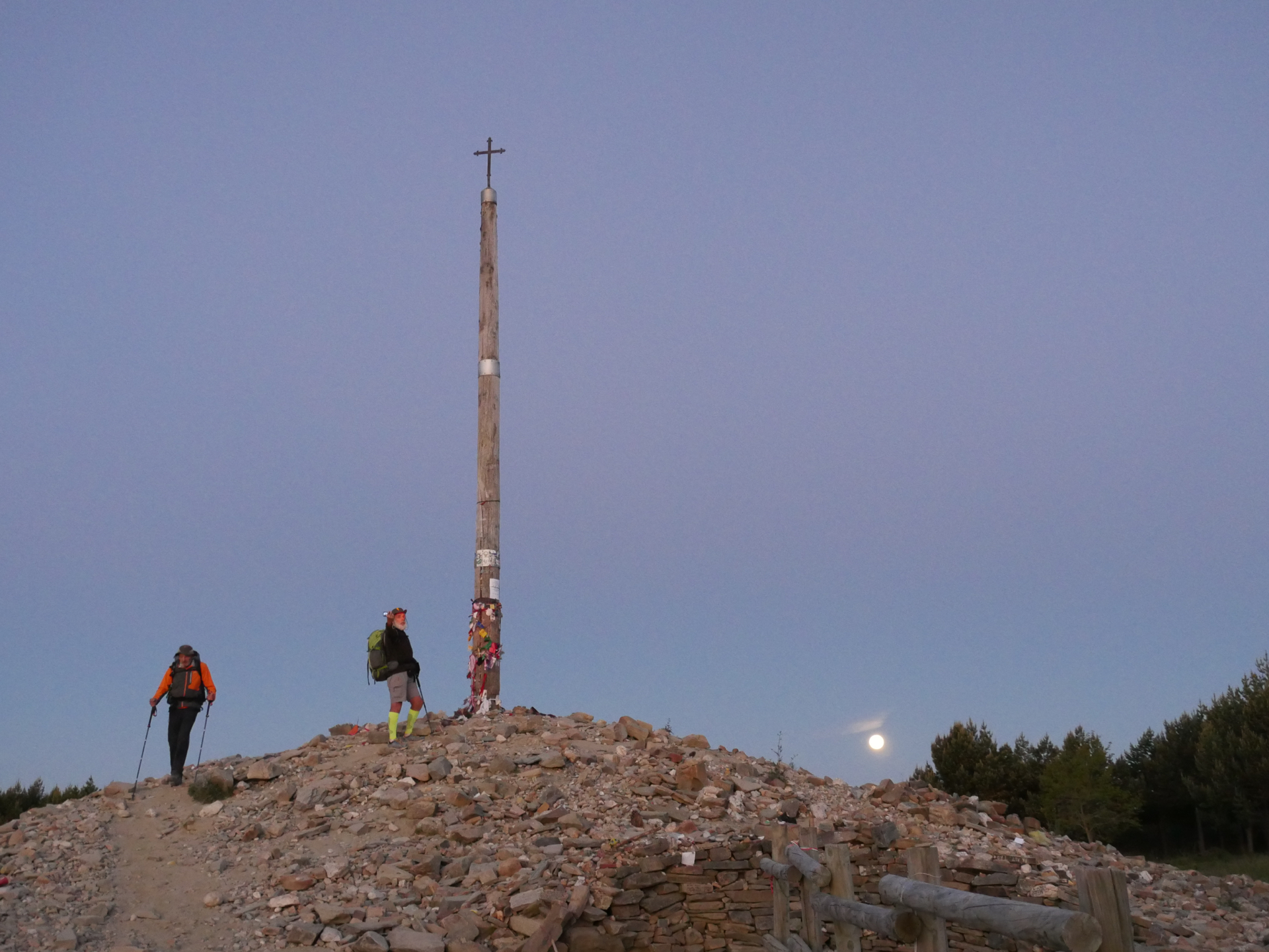 Cruz Ferro, an iron cross atop a wooden pole, stands in a pile of rocks representing pilgrims' burdens on the Camino de Santiago.