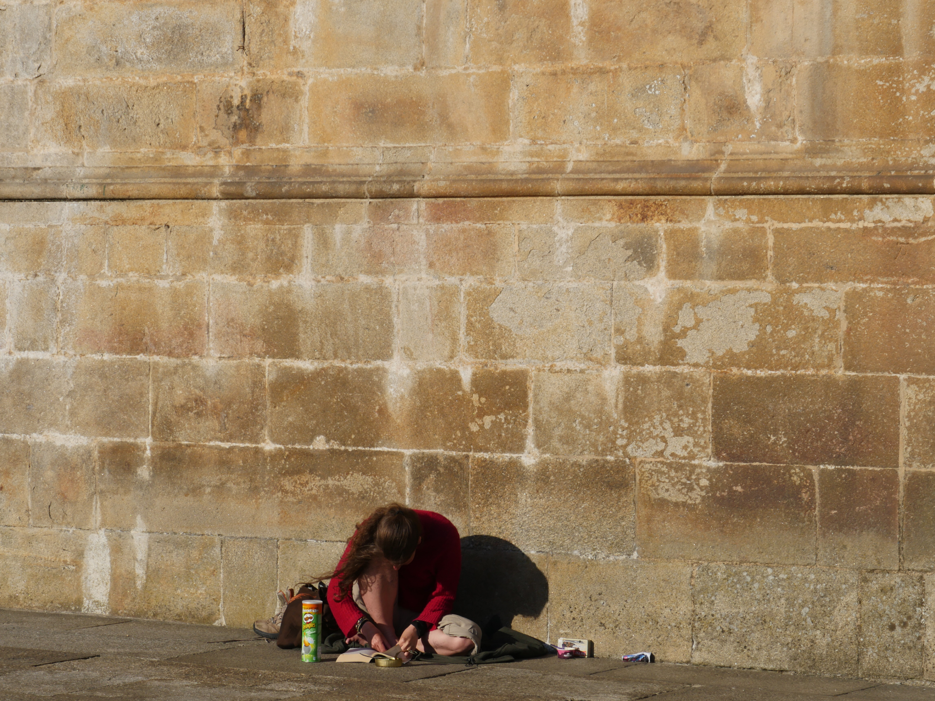 A Camino pilgrim reads a book next to the Santiago de Compostela Cathedral.