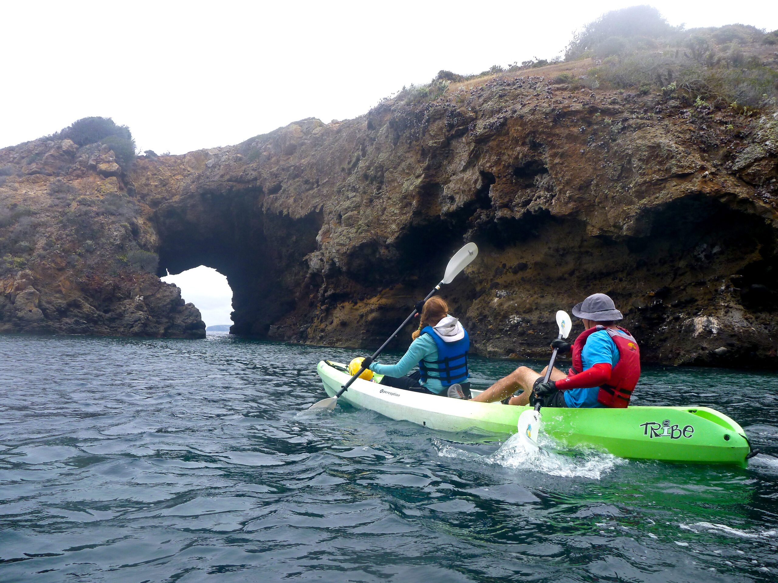 Kayakers get ready to paddle under an archway near Pelican Bay on Santa Cruz Island, California.