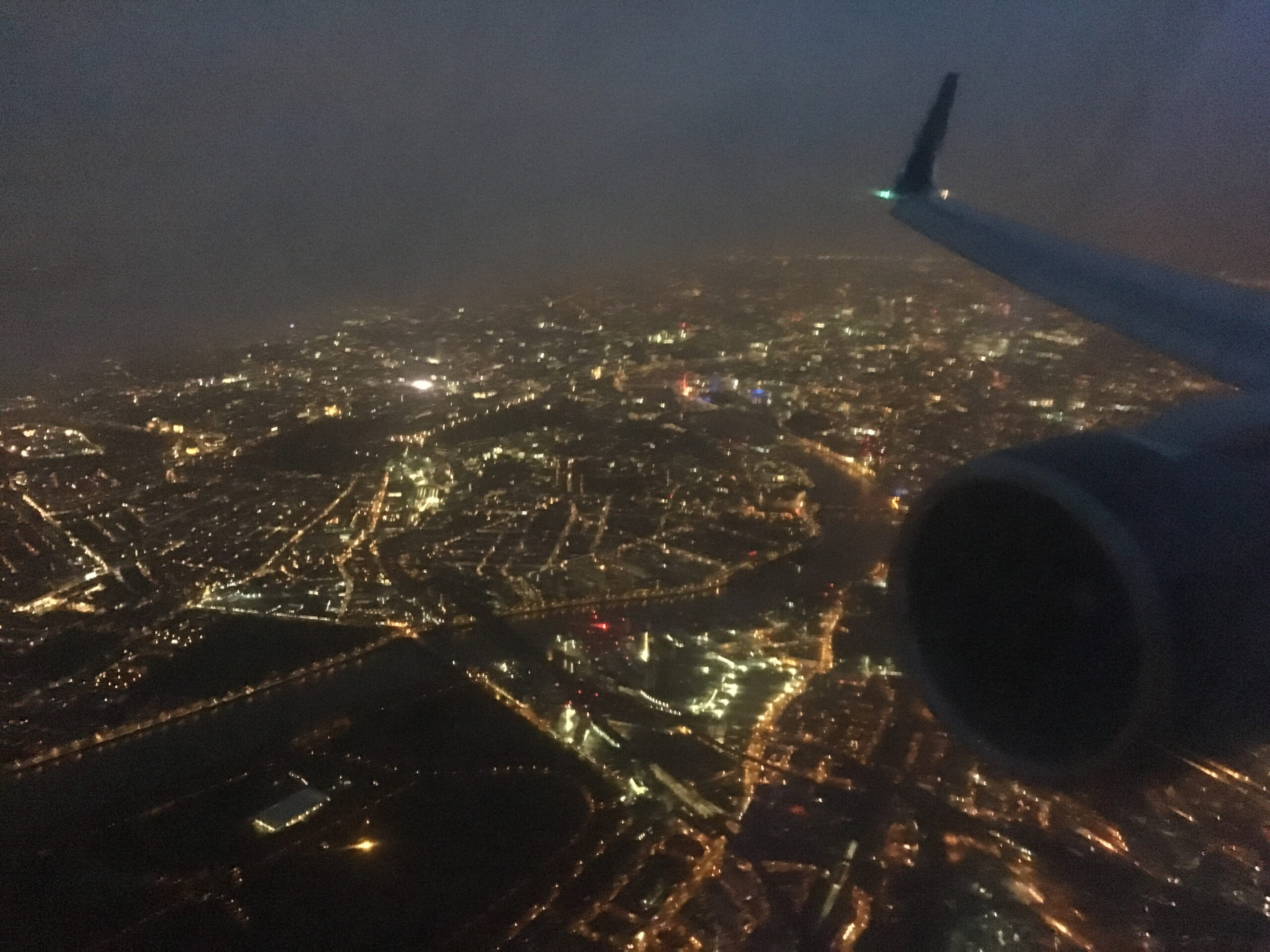 A Delta Airlines jet flies over foggy London, just before sunrise.
