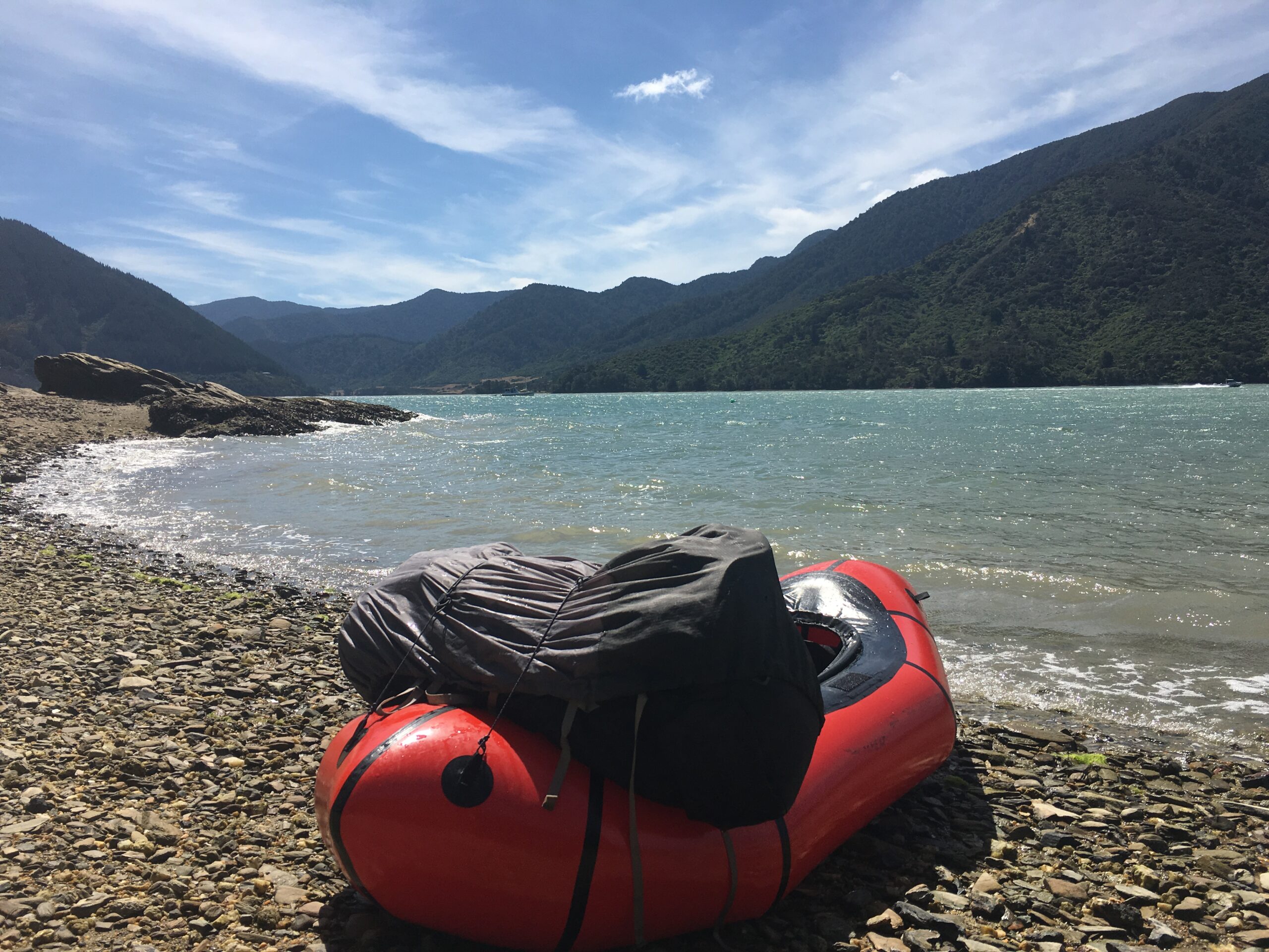 A packraft sits on a shoreline in Mahau Sound, New Zealand.