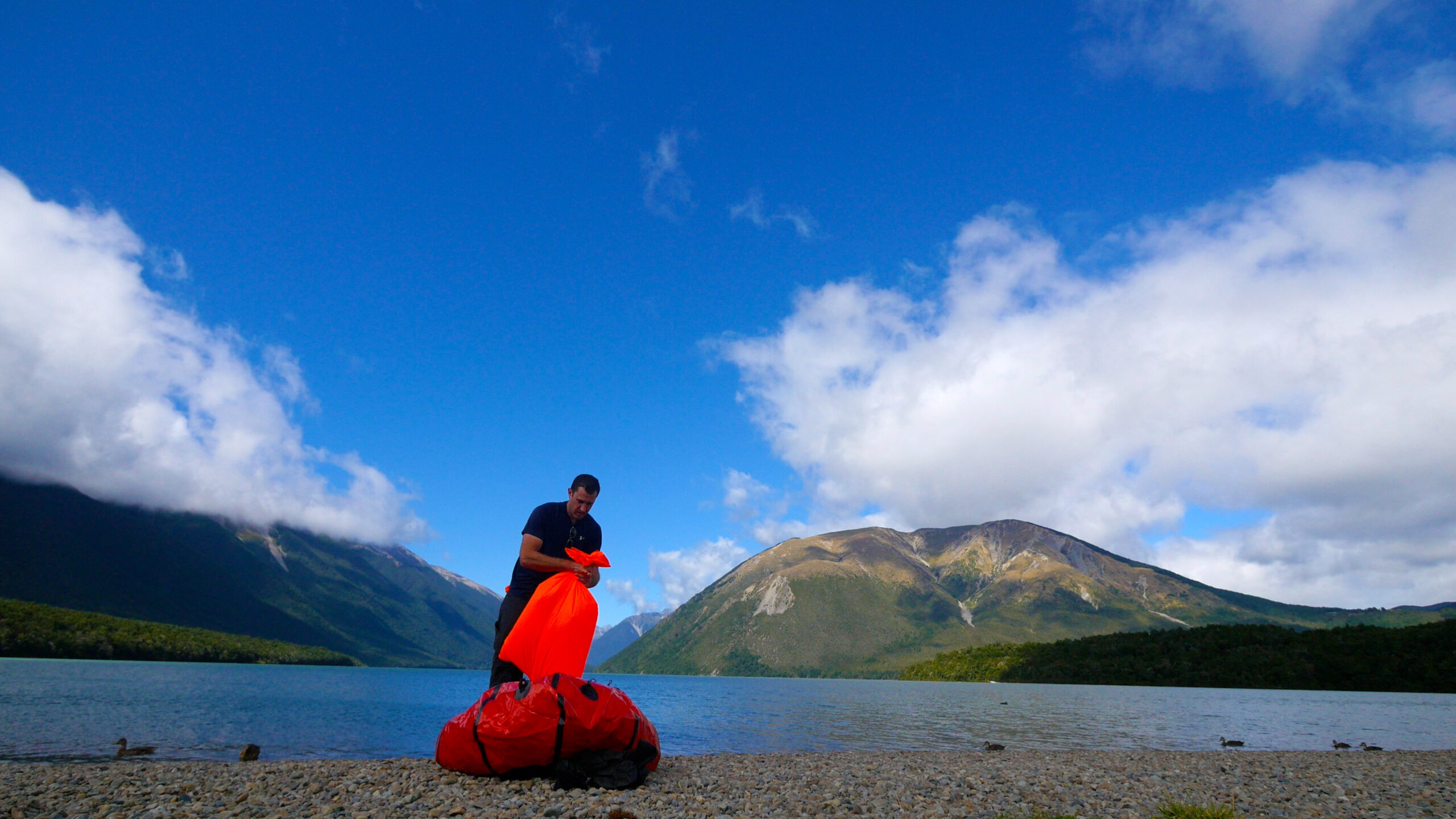 A rafter at Lake Rotoiti in St. Arnaud inflates a packraft by trapping air in a fabric bag and then squeezing the air into the raft.