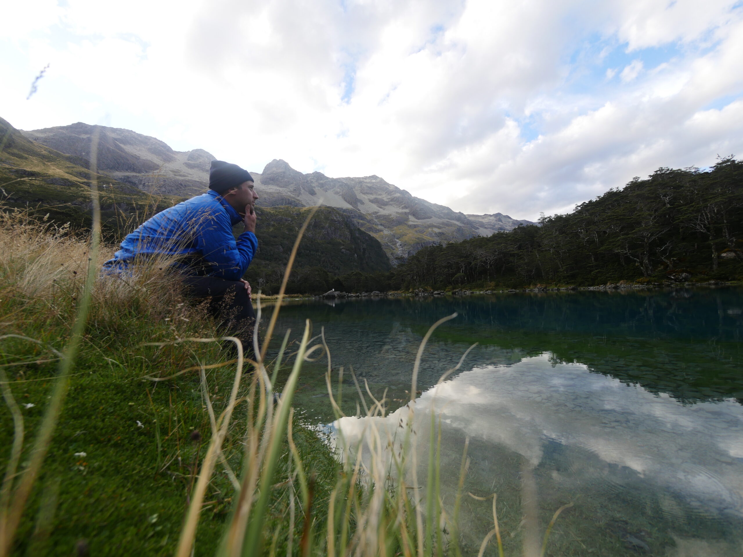 A hiker sits in Nelson Lakes National Park on the edge of Blue Lake, proven to be the clearest natural body of fresh water known to man.