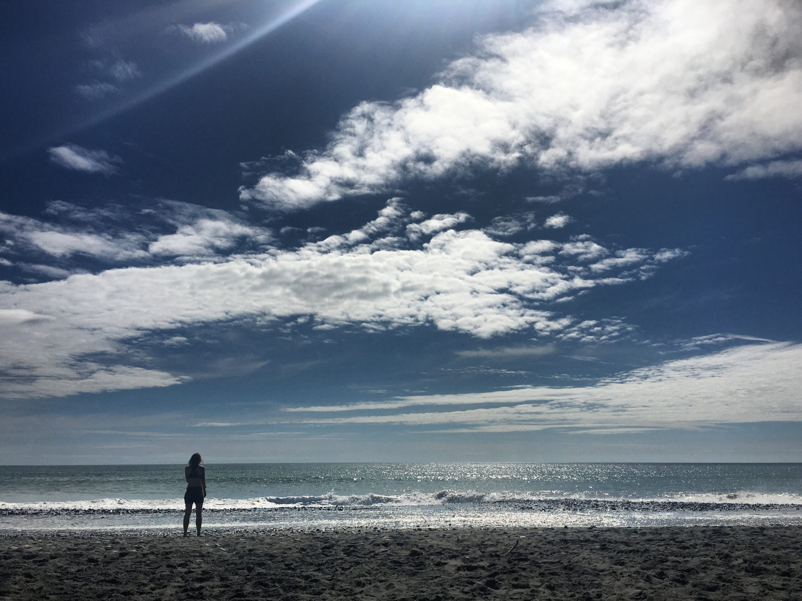 Charlotte stands on the beach in Hokitika.