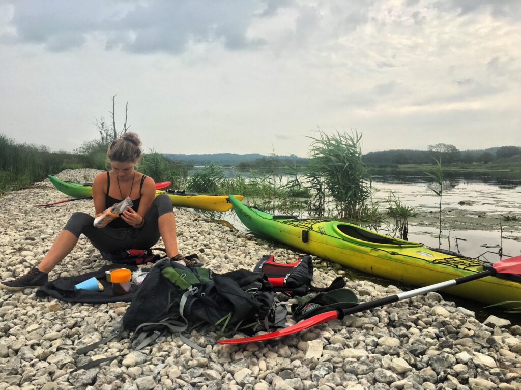 A kayaker eats lunch on the shore of the River Guden