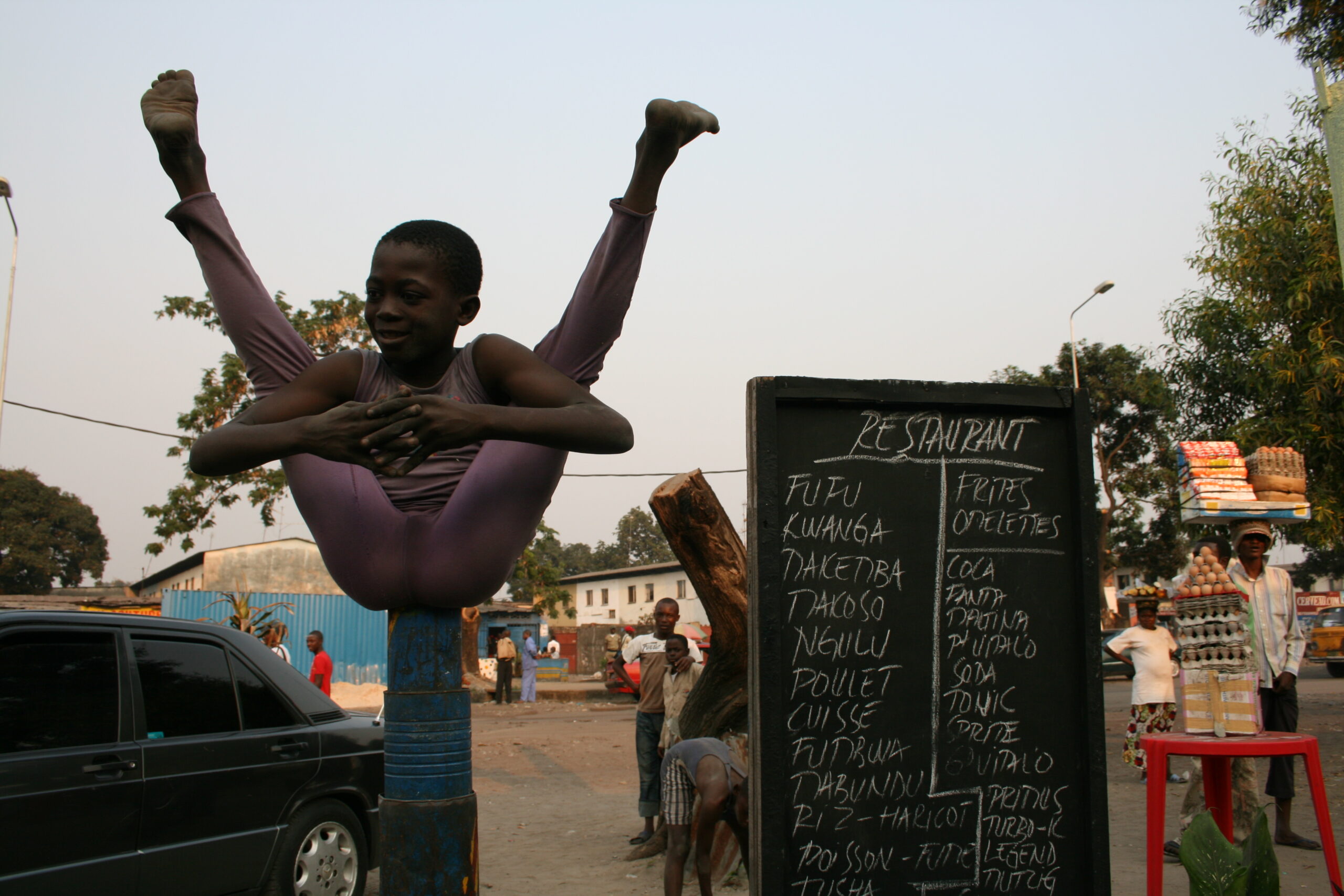 Child performing circus act near Kinshasa restaurant