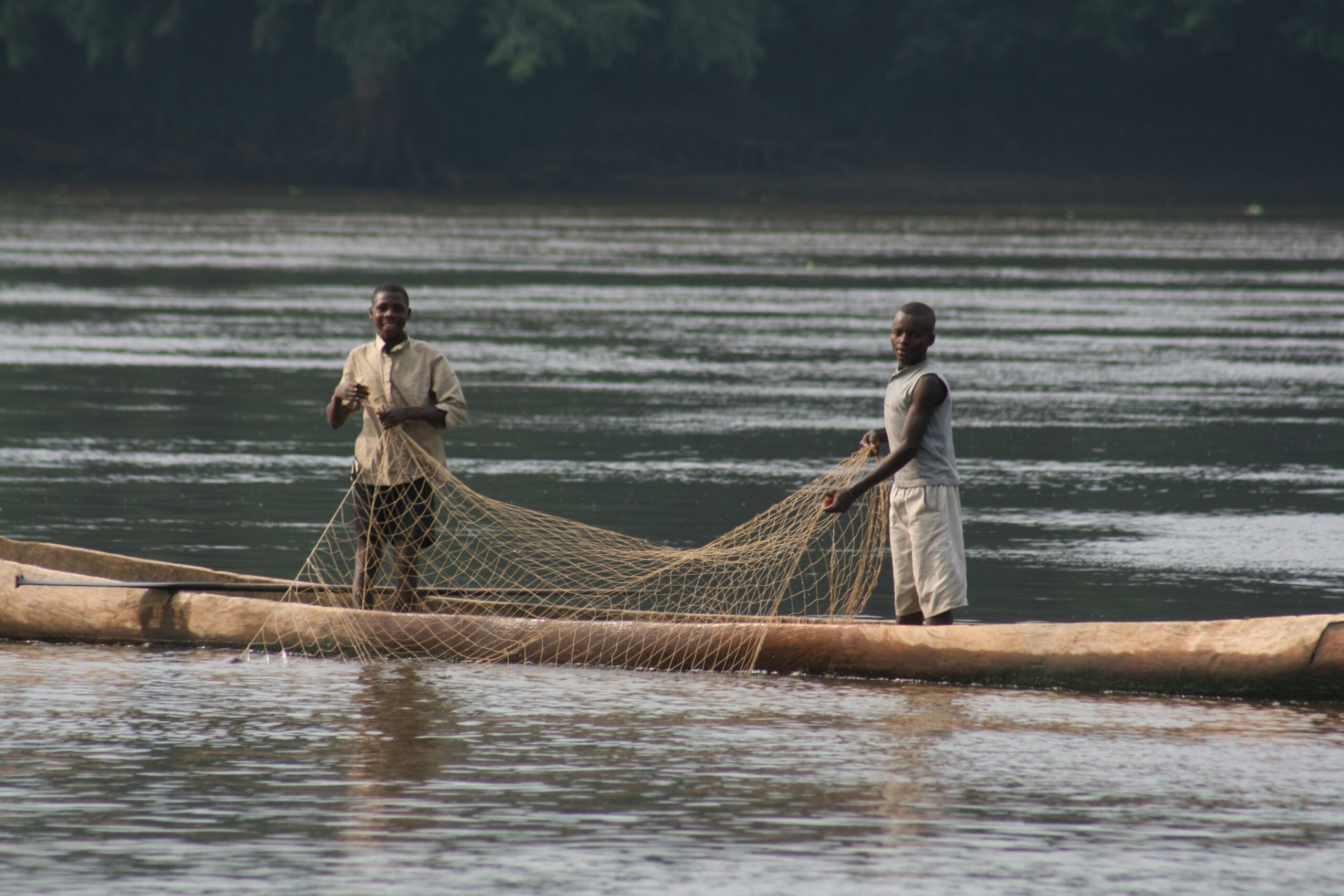Children fishing with net in pirogue