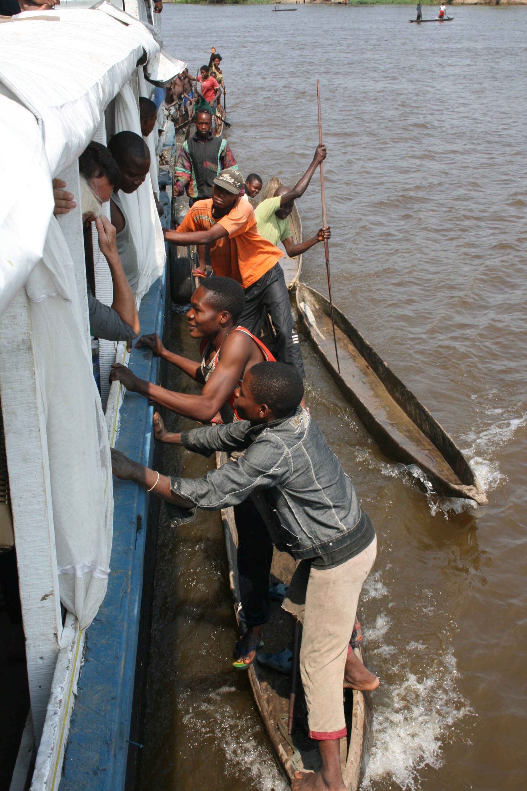 Men in pirogues holding on to boat