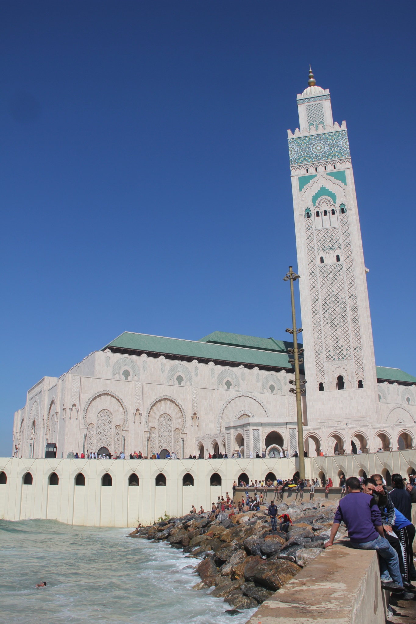 King Hassan II Mosque exterior with people on coast