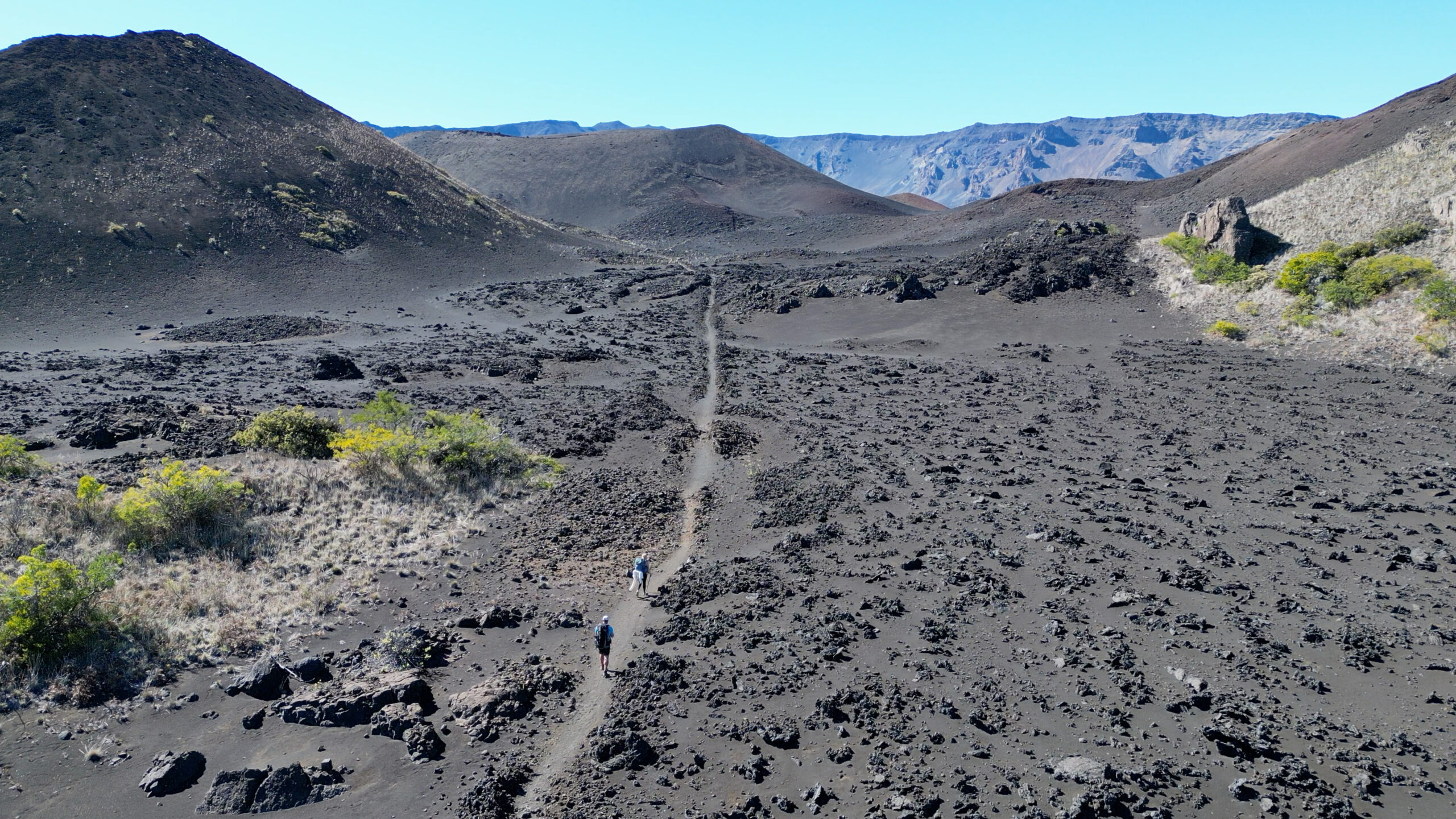 Backpackers hike through cooled lava.